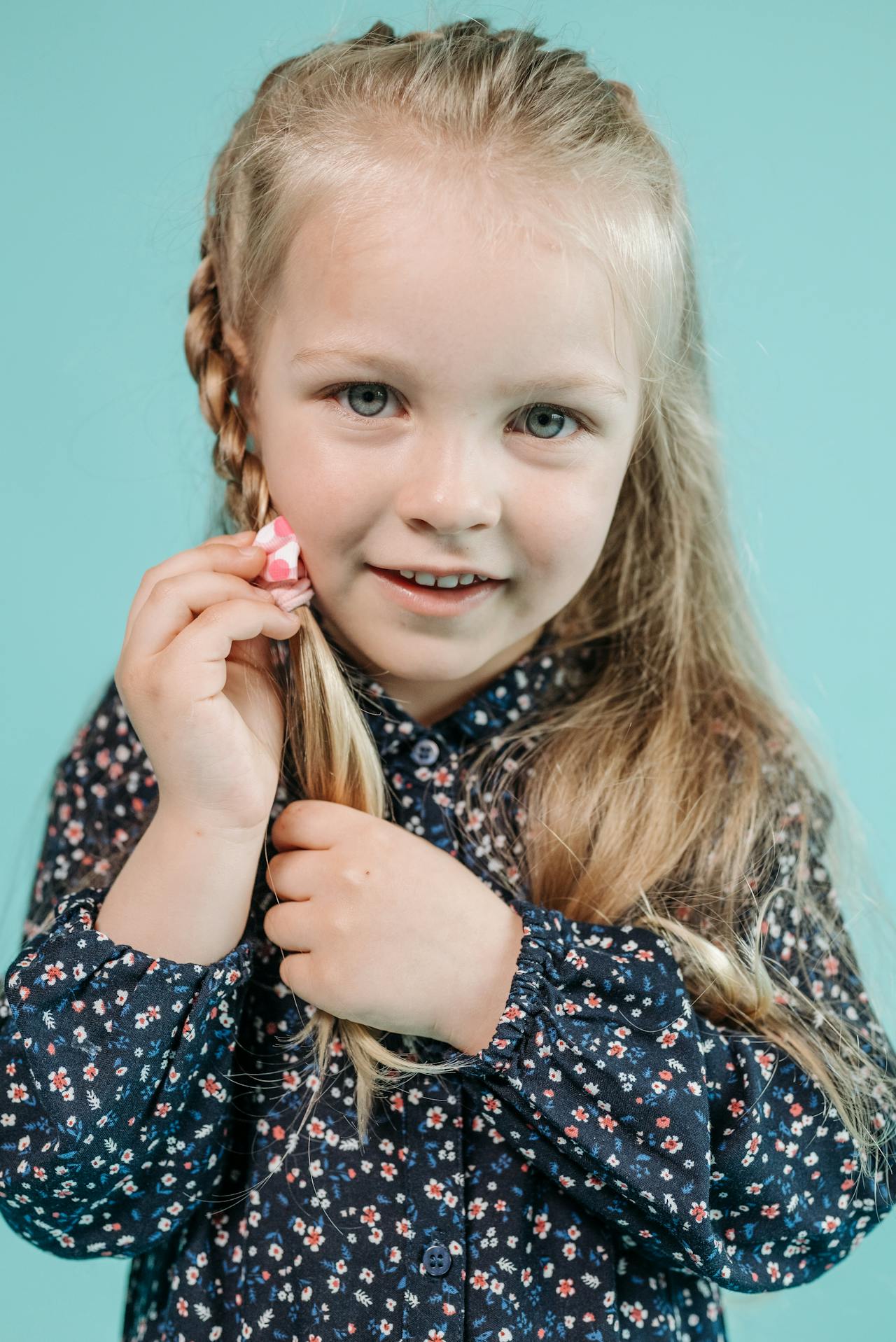 Une petite fille ravie tenant ses cheveux tressés | Source : Pexels