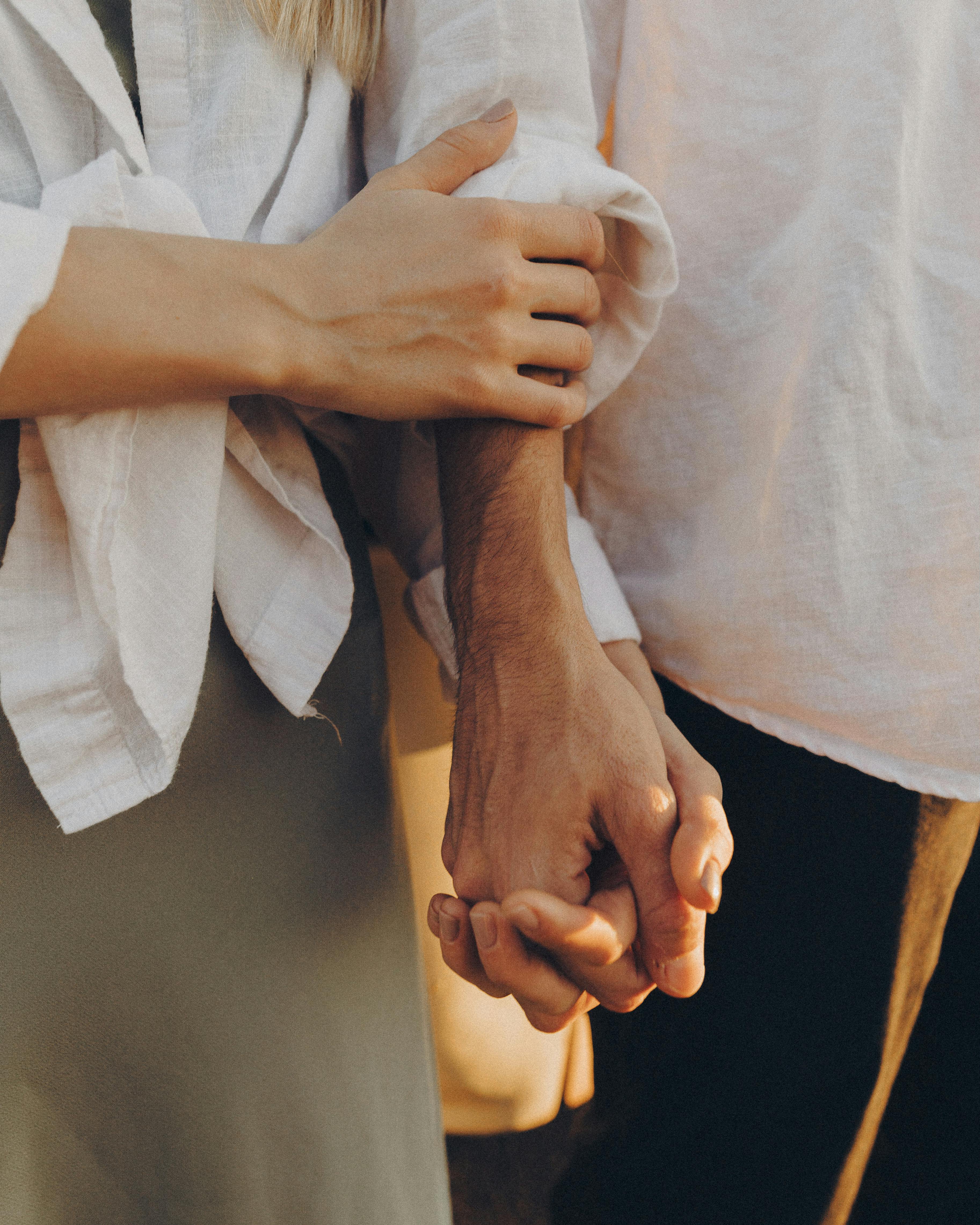 Une femme caresse le bras d'un homme tout en se tenant par la main | Source : Pexels