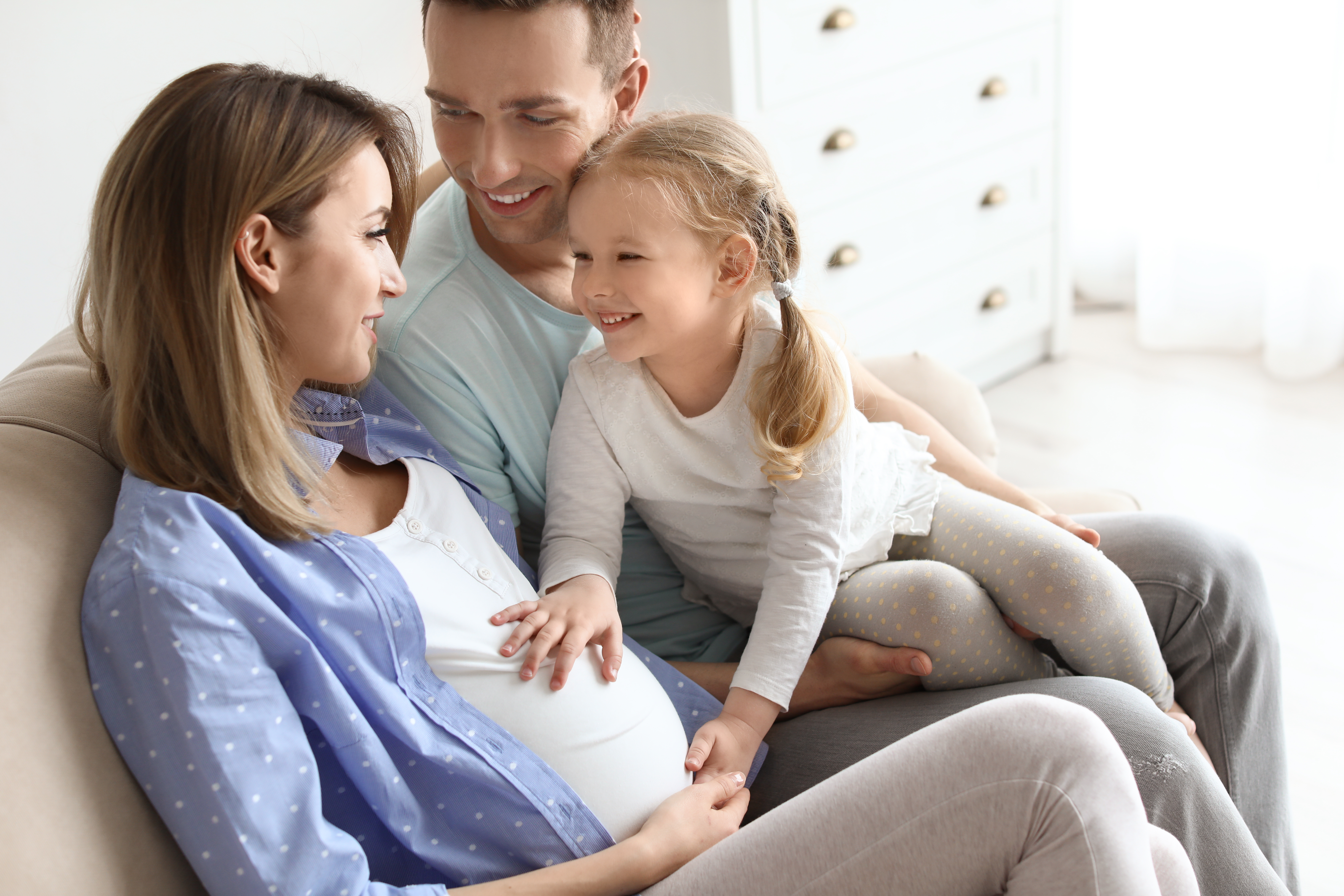 Une femme enceinte avec son mari et sa petite fille à la maison | Source : Shutterstock