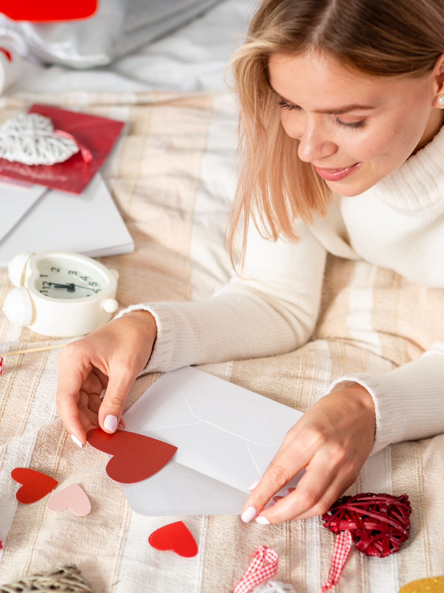 Une femme plaçant un morceau de papier en forme de cœur à l'intérieur d'une enveloppe | Source : Freepik