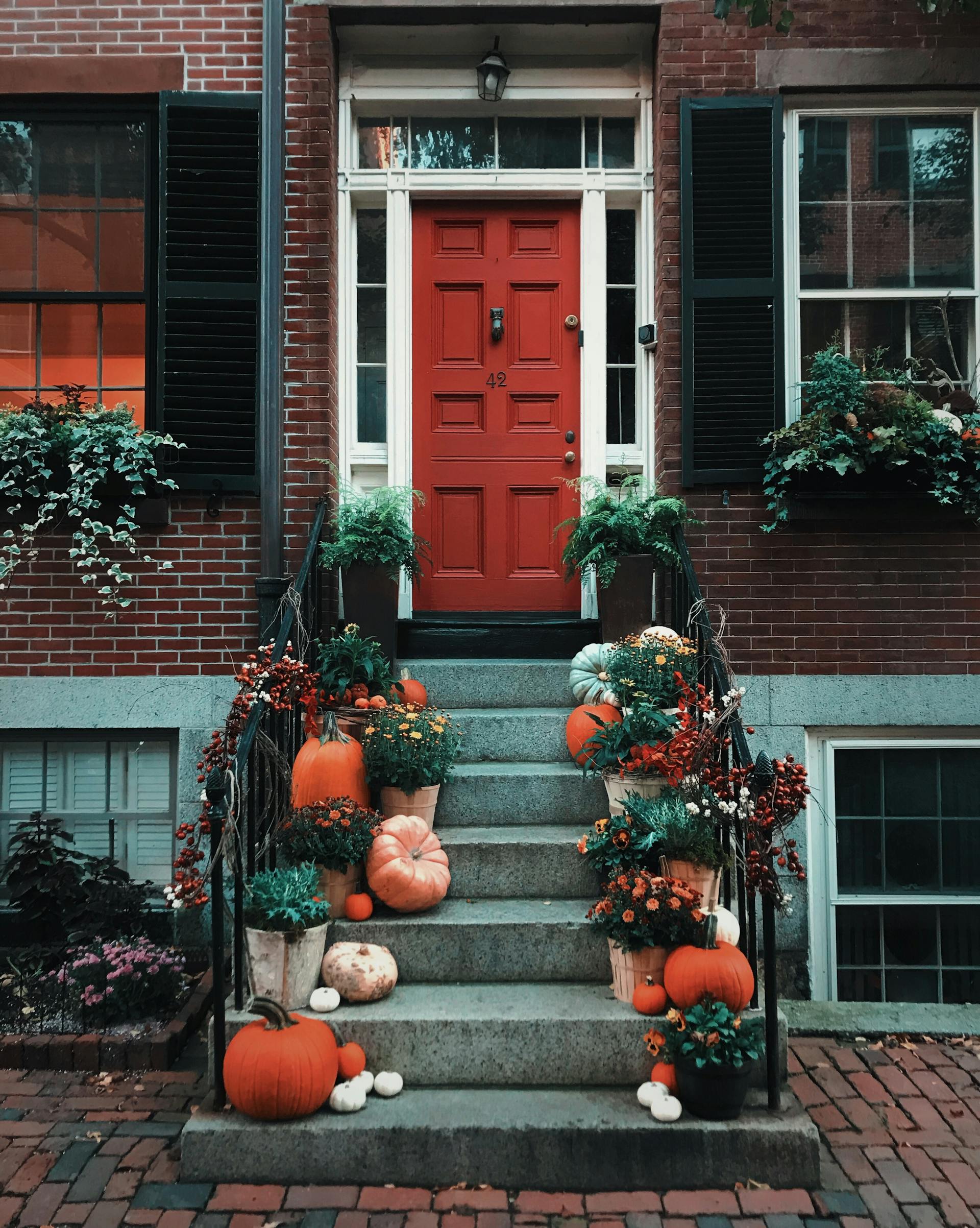 Des citrouilles sur les escaliers devant une porte | Source : Pexels