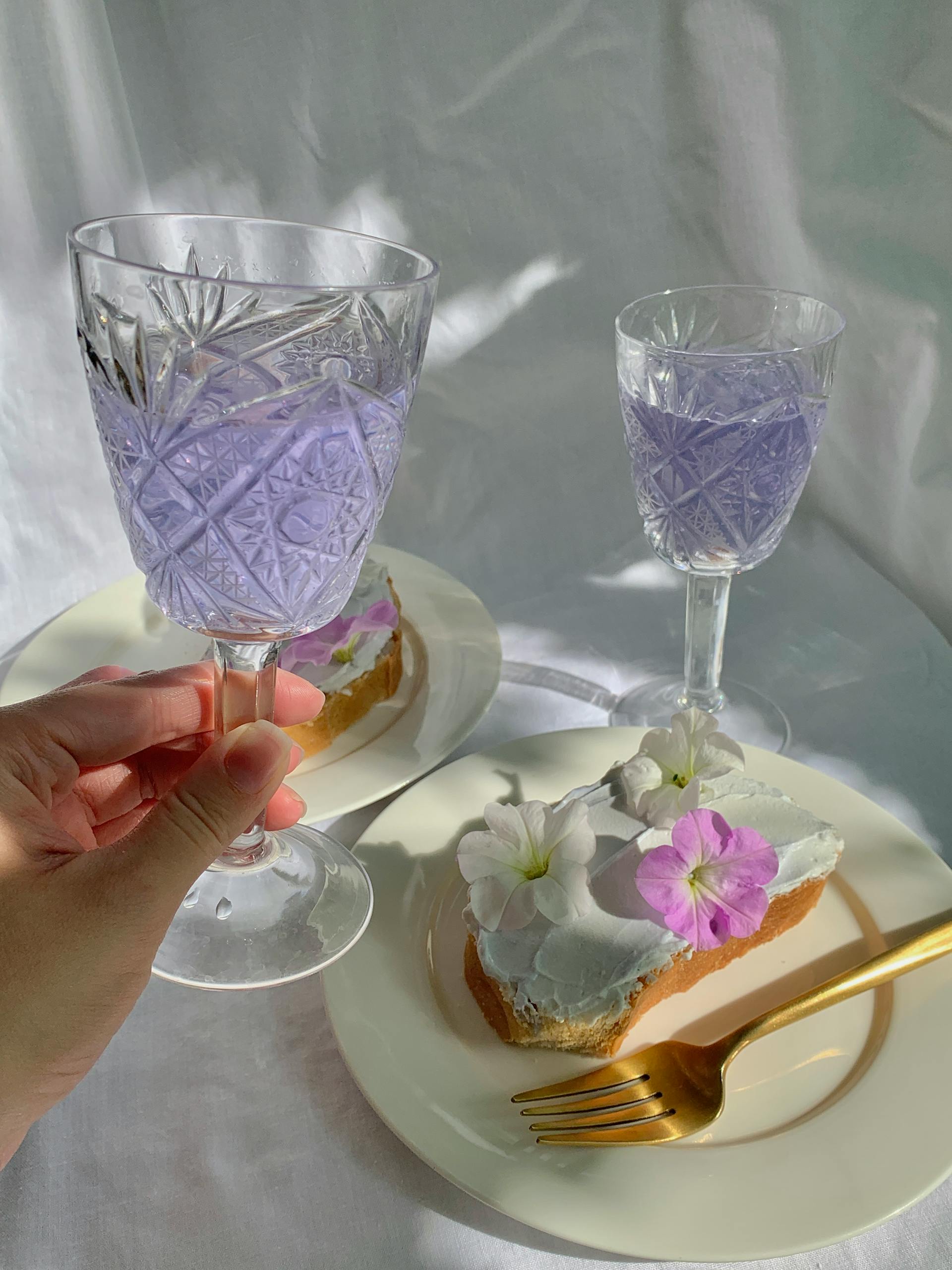 Une personne tenant un verre de vin en gobelet au-dessus d'une assiette avec des fleurs sur du pain | Source : Pexels