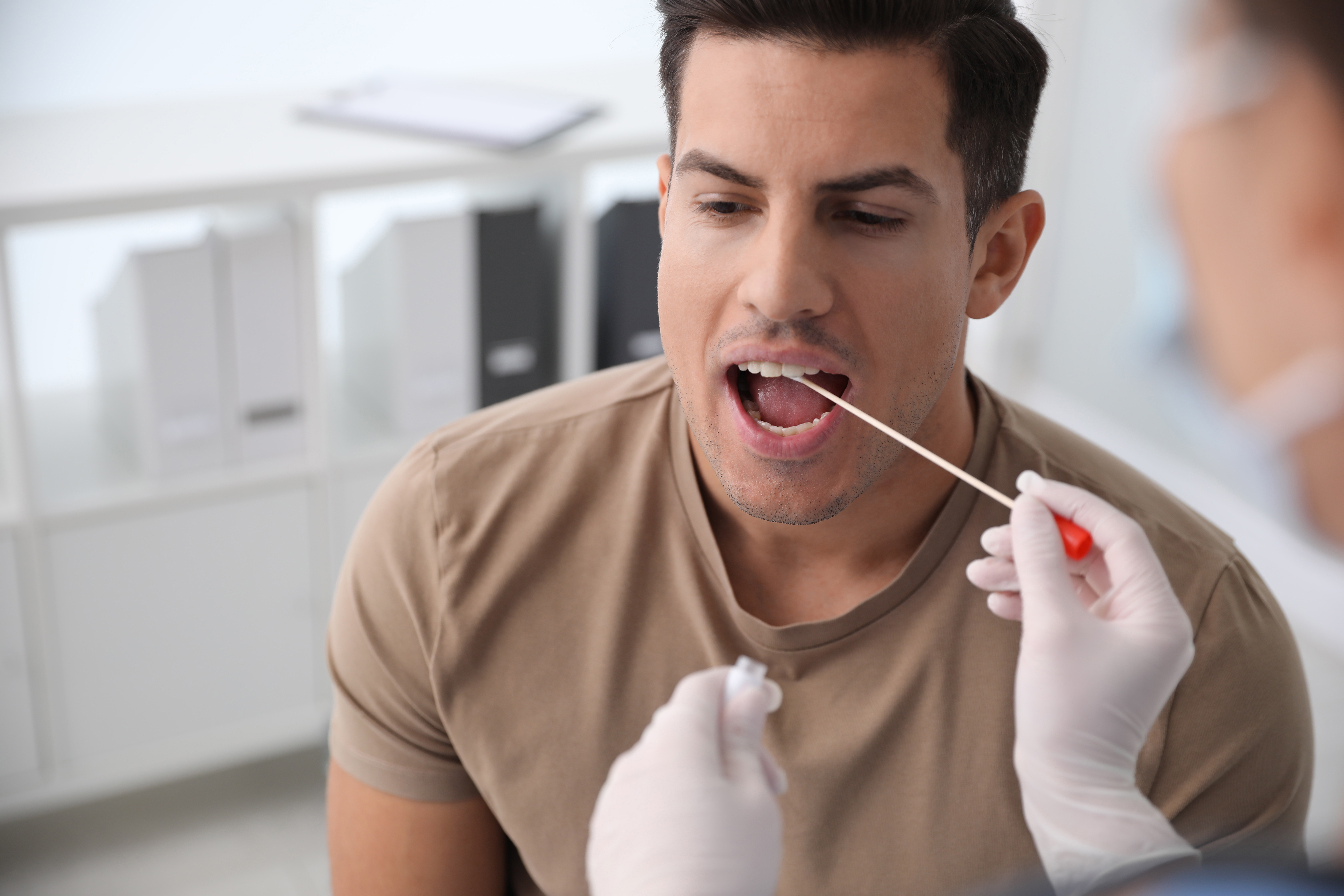Médecin prélevant un échantillon pour un test ADN sur un homme dans une clinique | Source : Shutterstock
