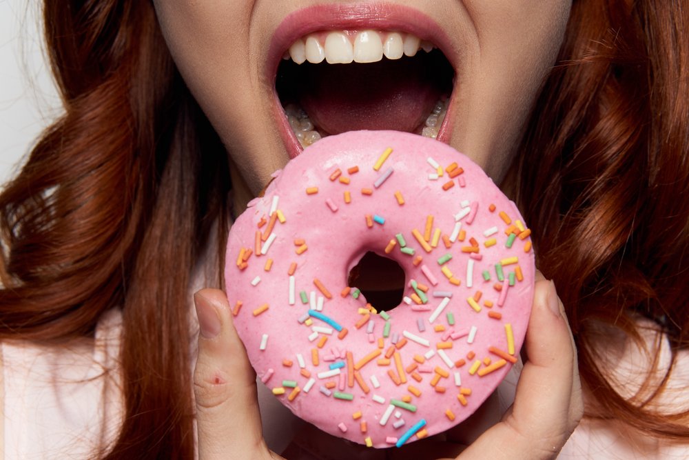 Une femme sur le point de manger un beignet. || Photo : Shutterstock