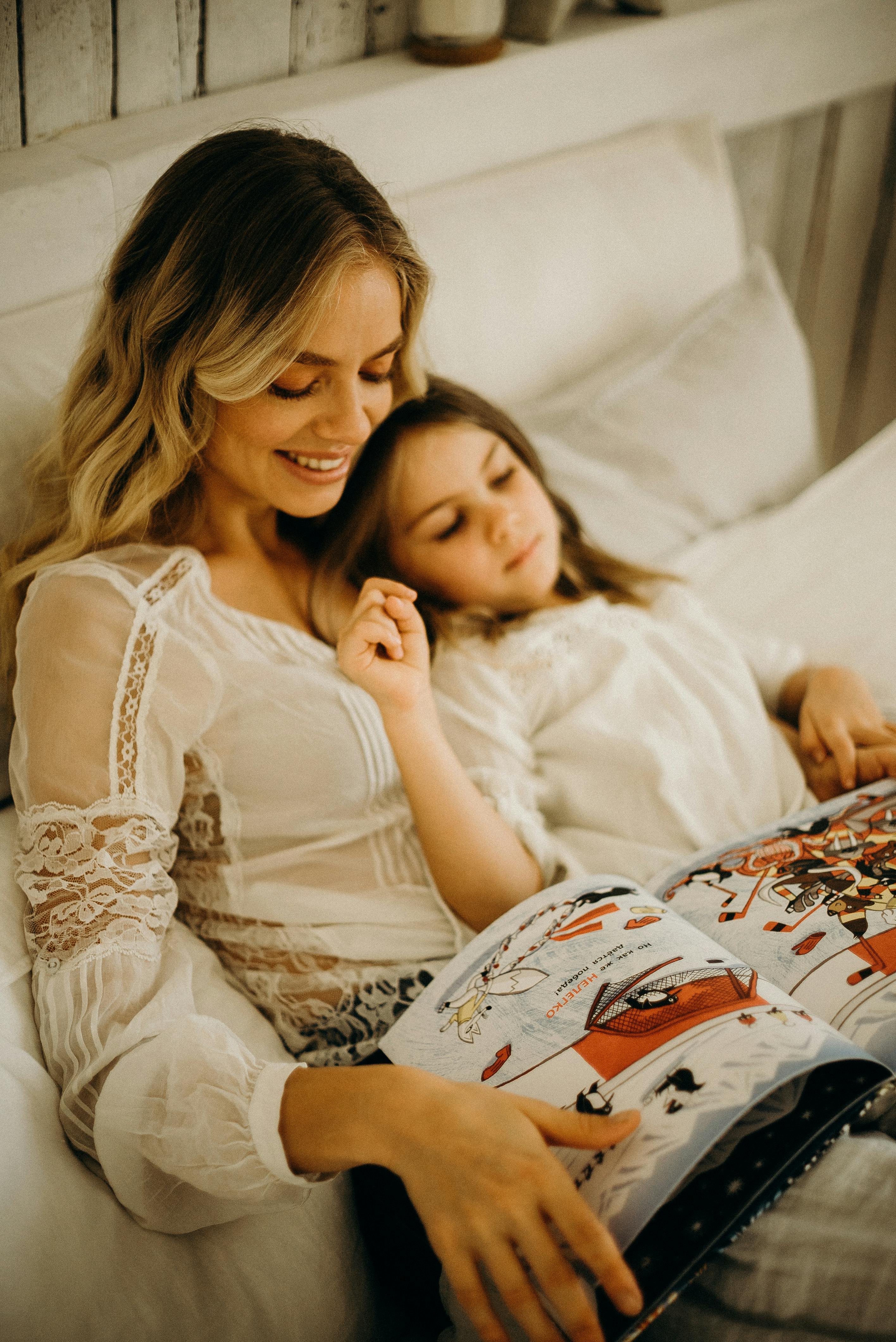 Une femme bordant une petite fille dans son lit | Source : Pexels