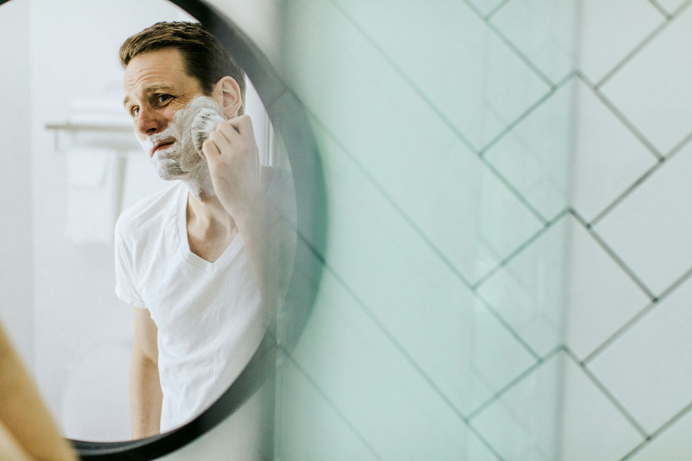 Un homme se rasant dans un miroir | Source : Unsplash