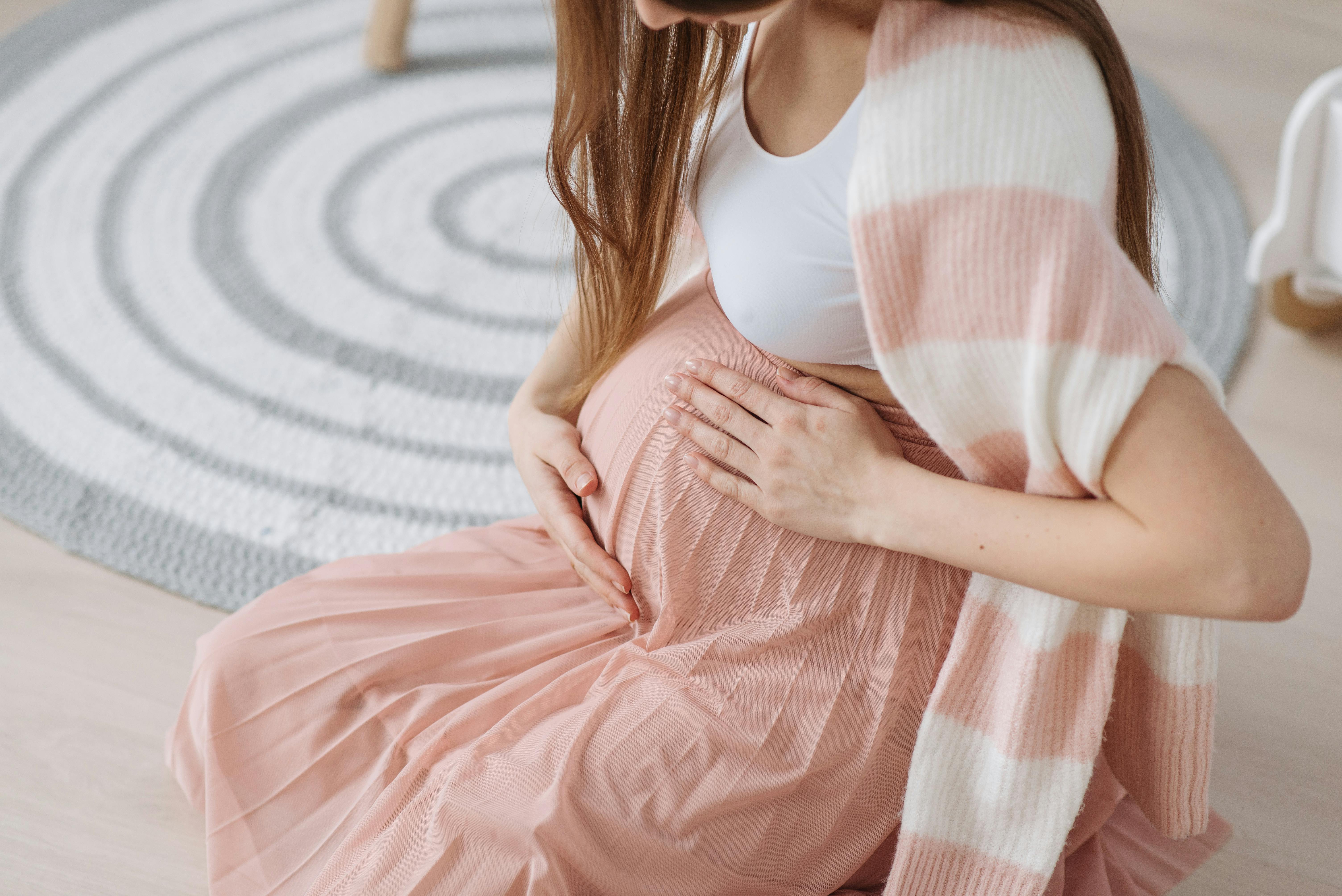 Une femme enceinte se tenant le ventre en position assise | Source : Pexels
