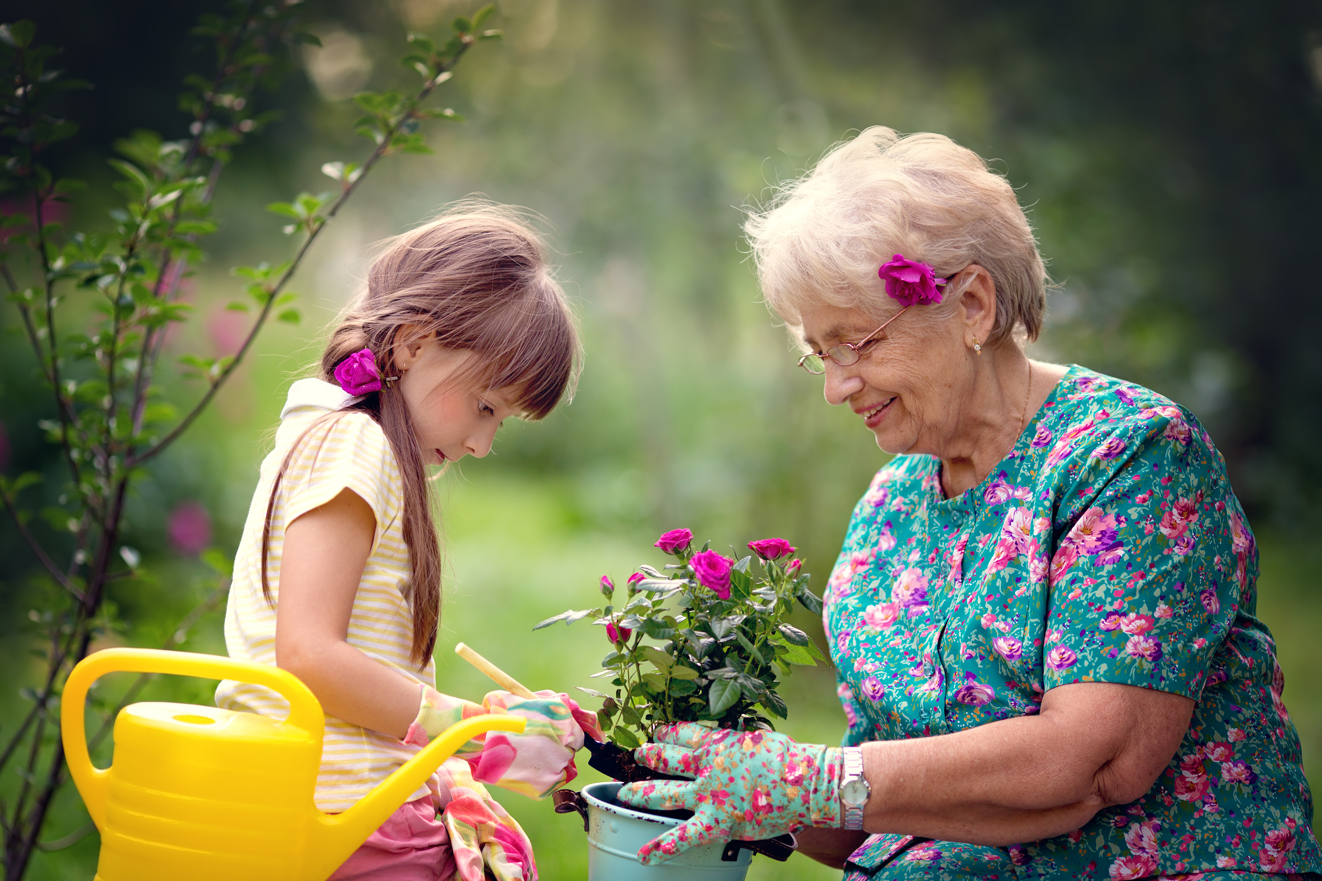 Une grand-mère heureuse travaille dans le jardin avec sa petite fille. | Source : Shutterstock