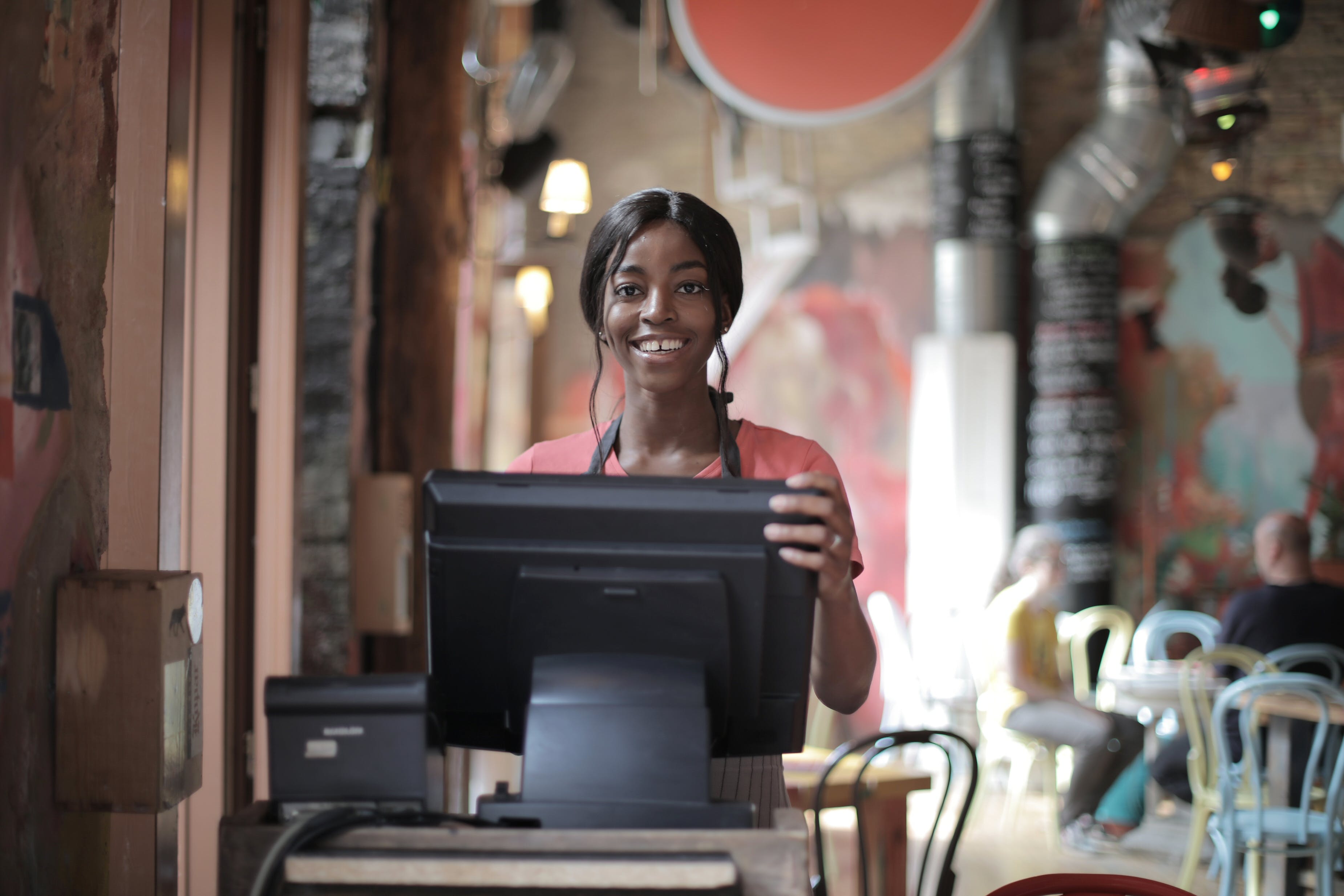 Une serveuse souriant alors qu'elle se tient derrière le comptoir | Source : Pexels
