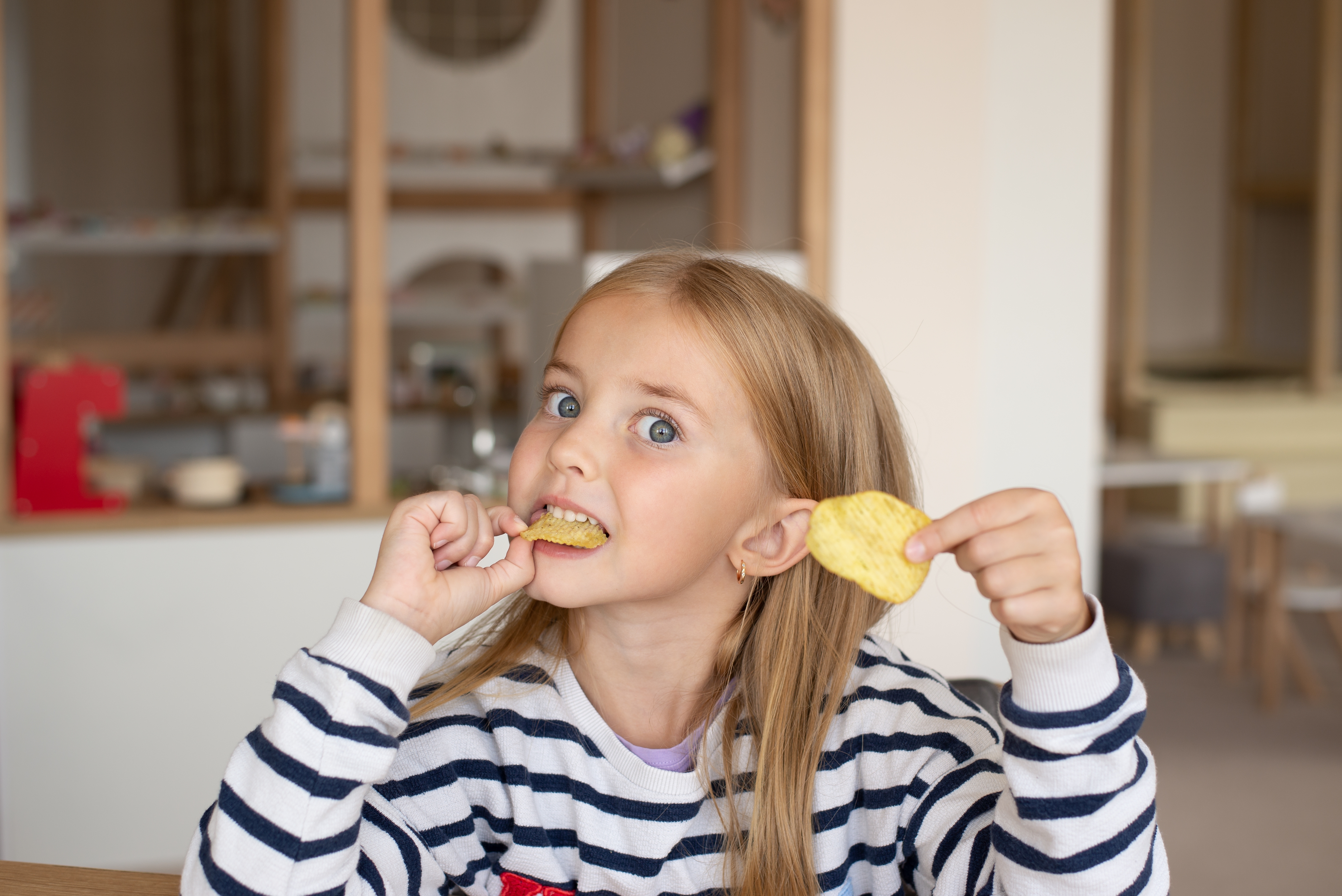 Une petite fille qui mange des chips | Source : Shutterstock