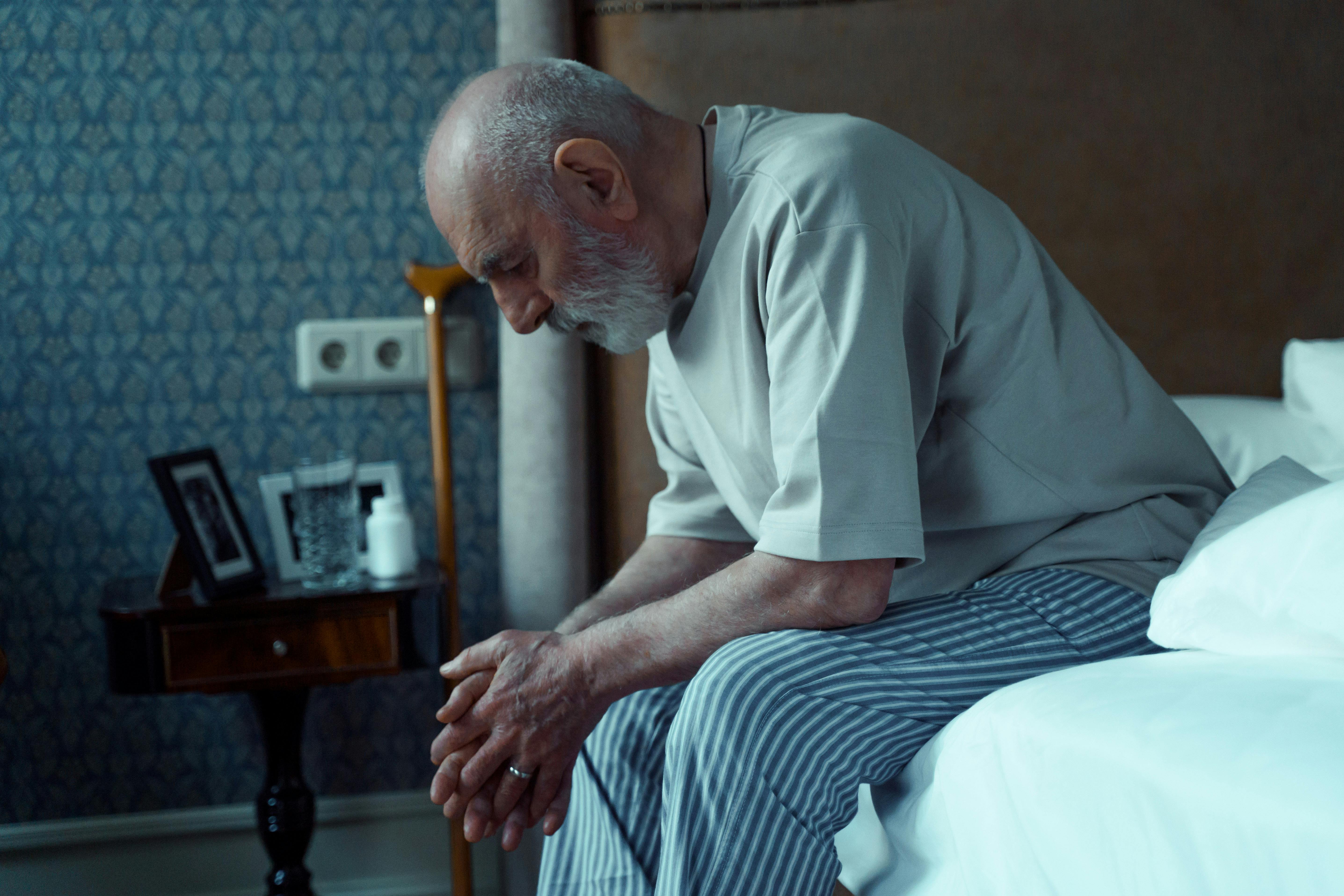 Un homme à l'air malade est assis sur un lit | Source : Pexels