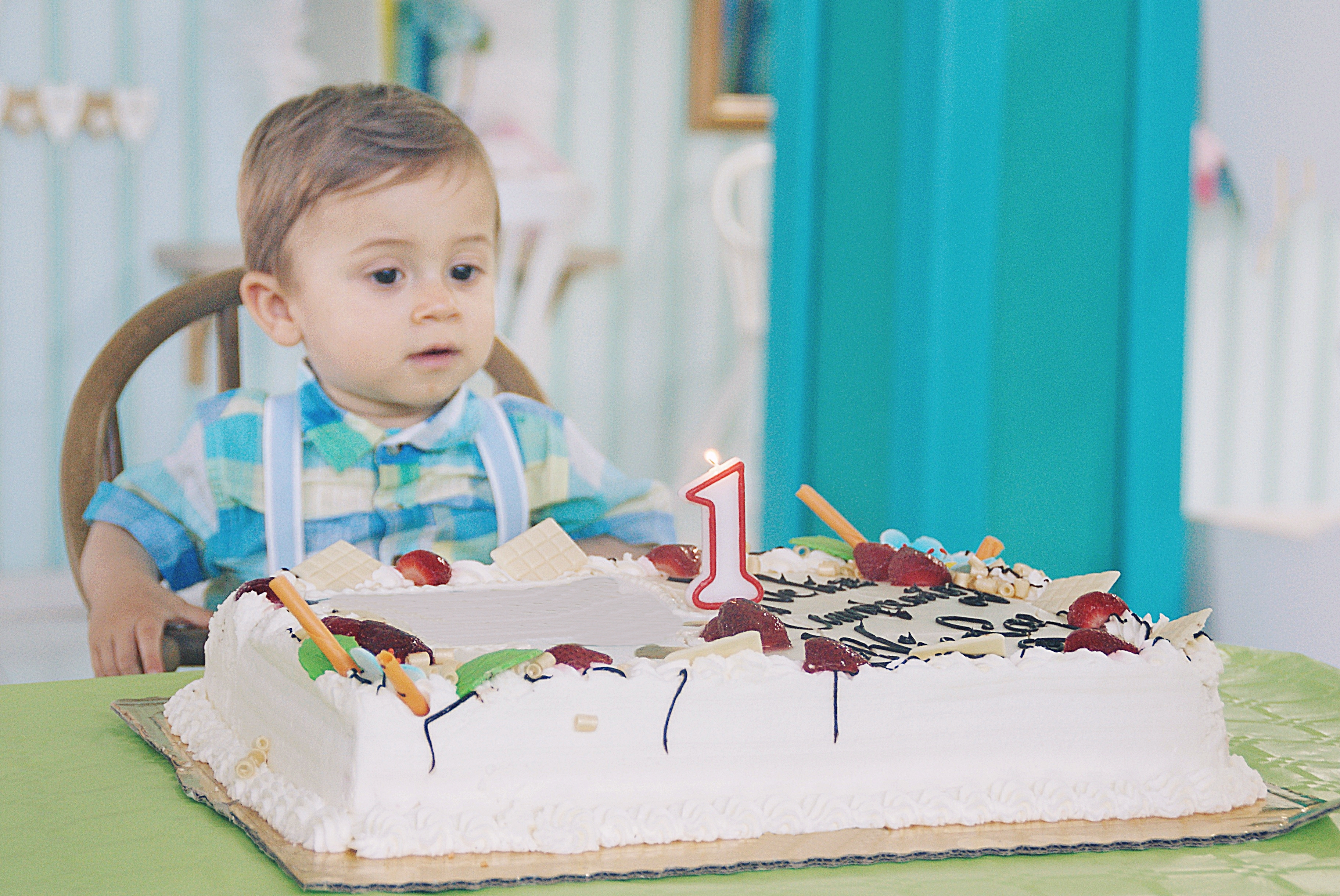 Portrait d'un enfant assis à une table, prêt à souffler la bougie de son gâteau d'anniversaire | Source : Getty Images