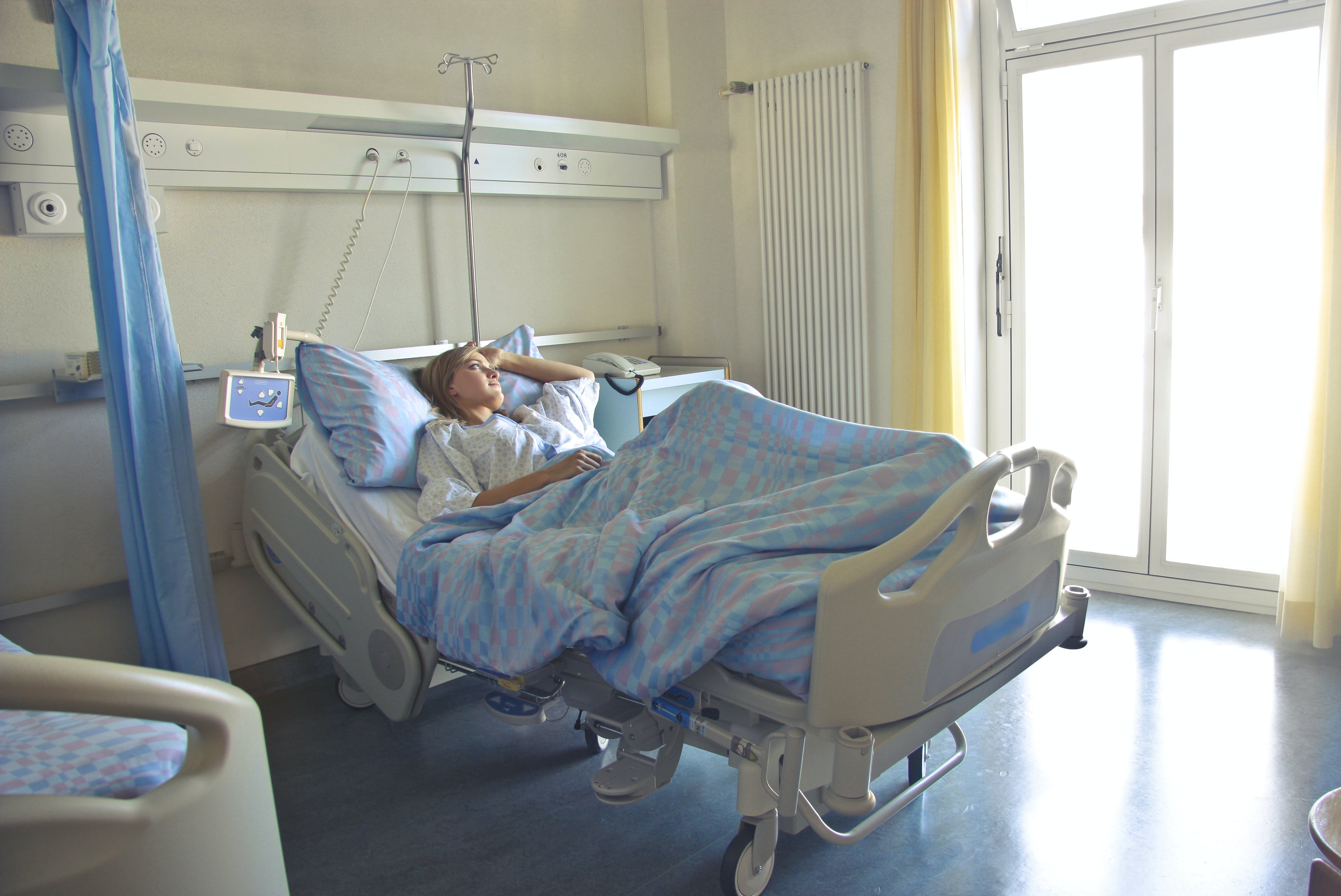 Une femme allongée sur un lit d'hôpital, seule dans sa chambre | Source : Pexels