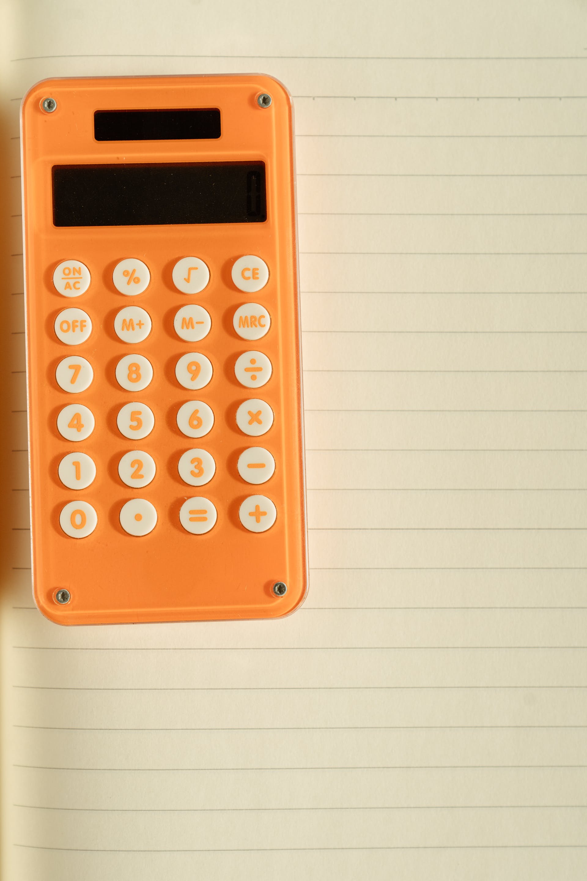 Une calculatrice orange sur du papier blanc | Source : Pexels