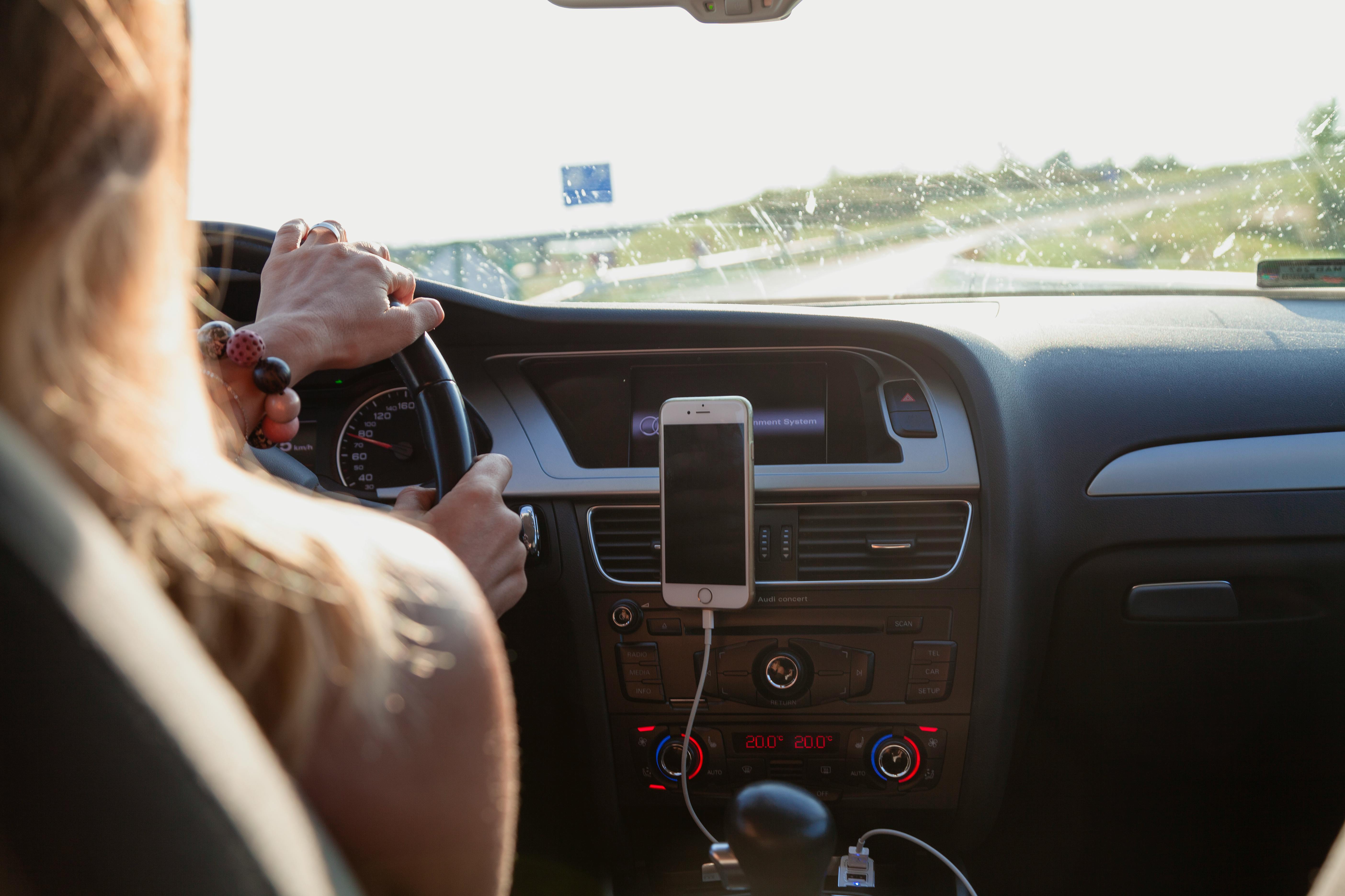 Une femme conduisant avec son téléphone branché dans sa voiture | Source : Pexels