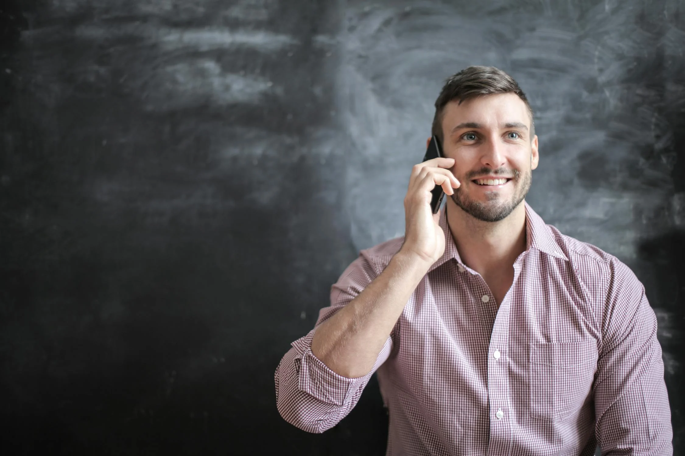 Un homme souriant qui parle au téléphone | Source : Pexels
