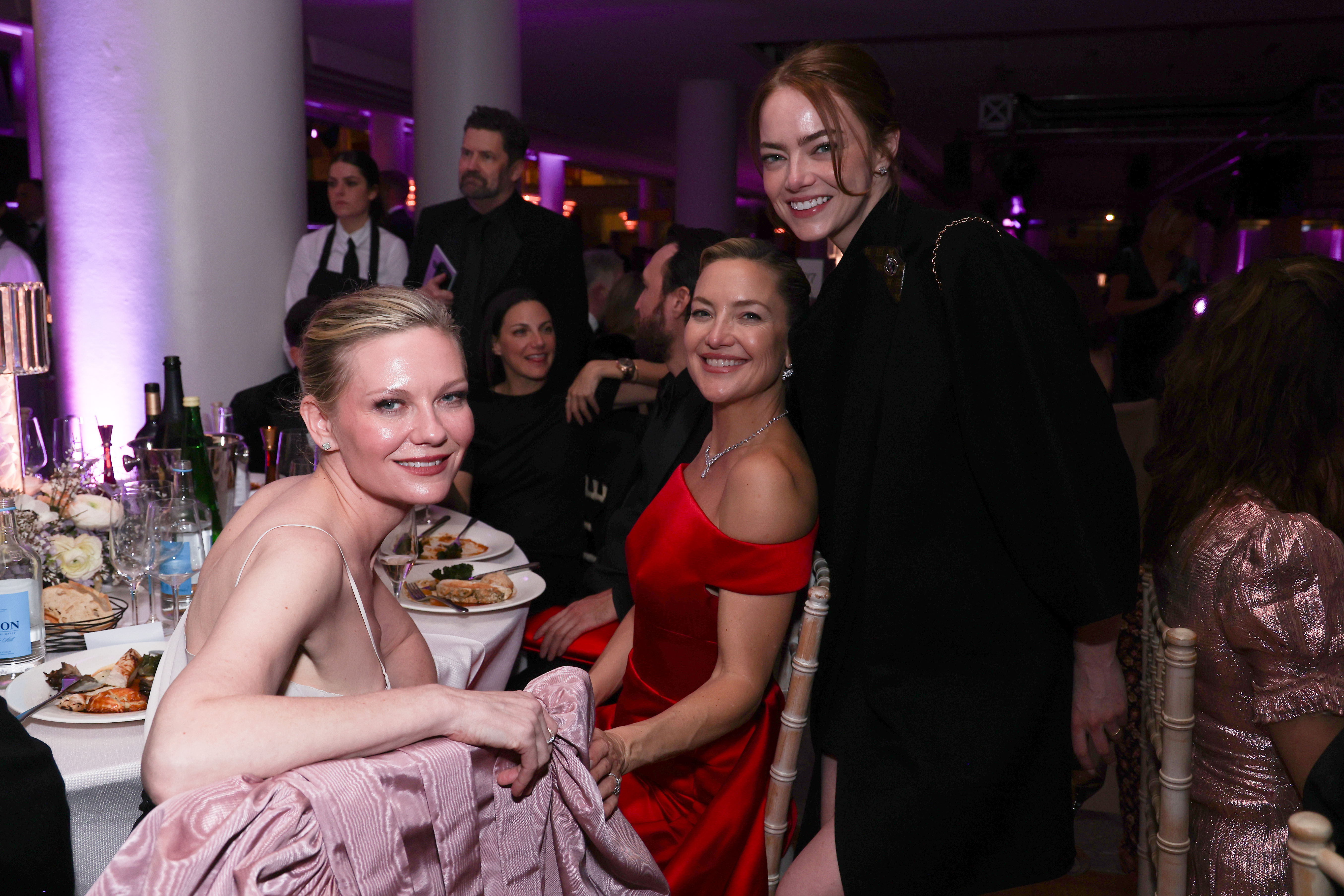 Emma Stone rejoint Kirsten Dunst et Kate Hudson à leur table, se penchant vers elles avec un sourire radieux alors que le trio partage un instantané spontané au milieu du dîner et de la conversation.
