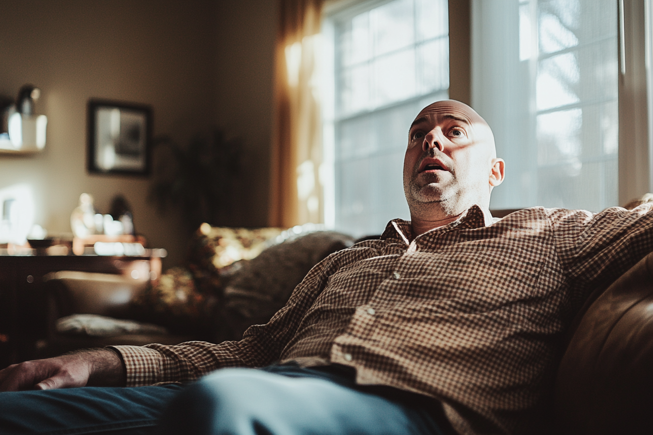 A man sitting on a sofa, looking up worriedly | Source: Midjourney