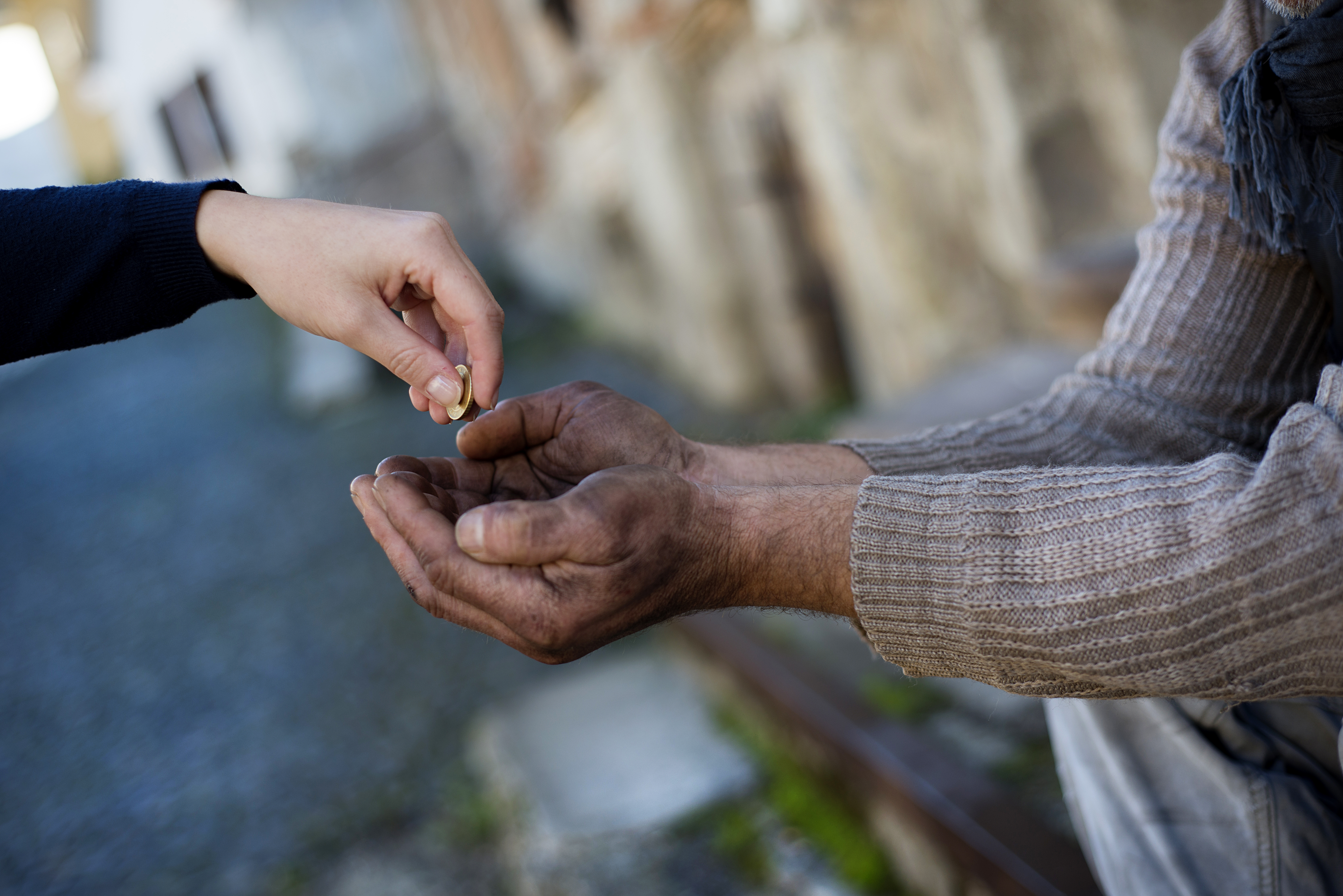 Quelqu'un donne de la monnaie à un sans-abri. | Source : Shutterstock