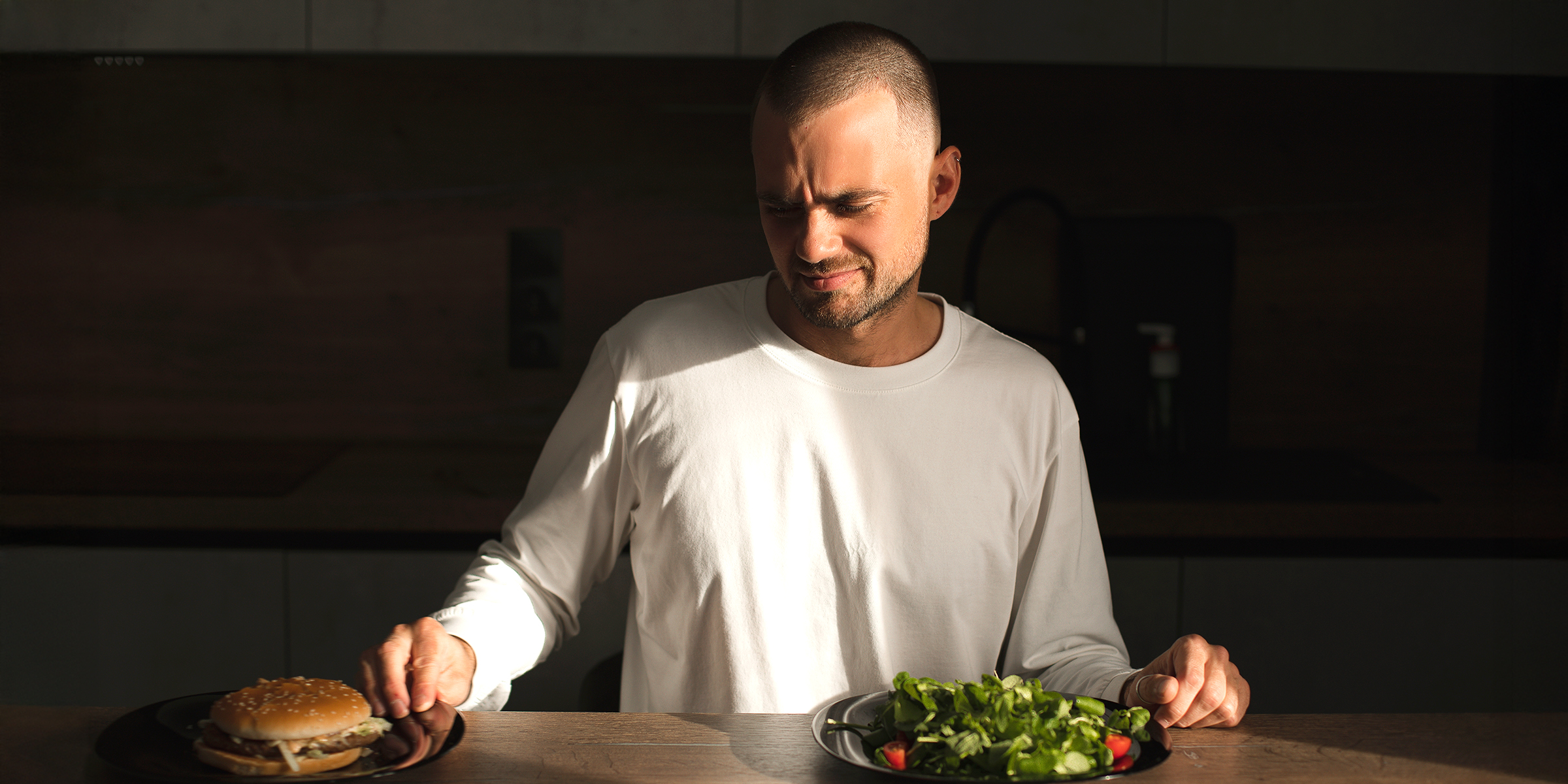 Un homme regardant une assiette de hamburgers | Source : Shutterstock