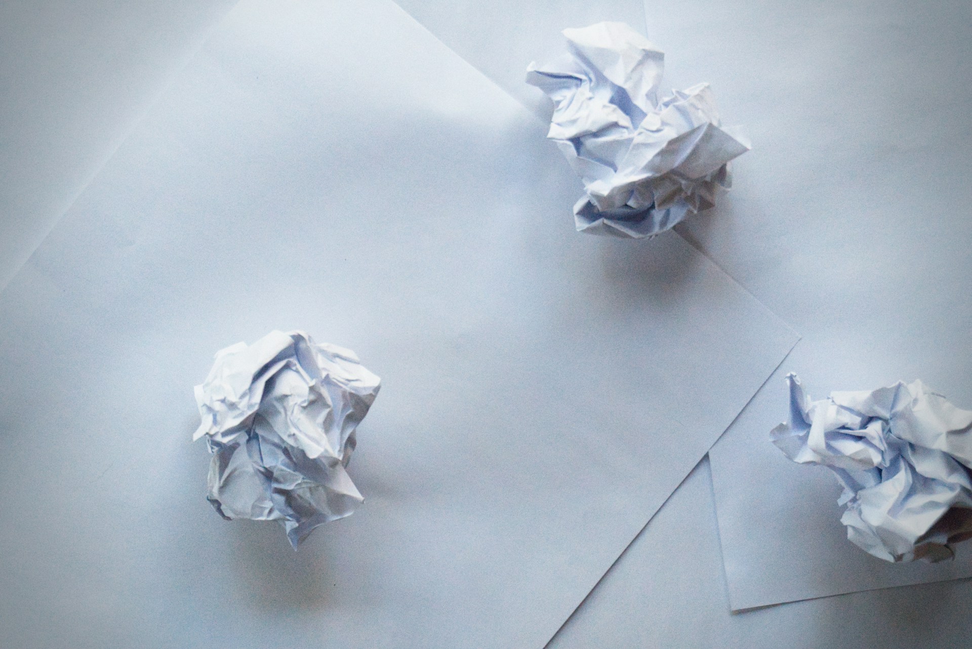 Boules de papier froissé et feuilles de papier sur une surface | Source : Unsplash