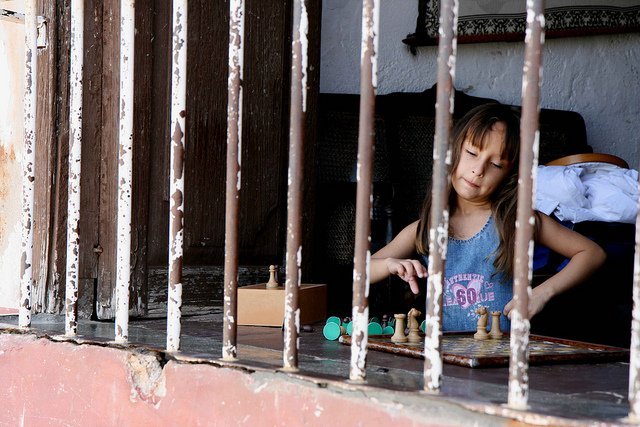 Une petite fille qui joue seule chez elle aux échecs. l Source: Flickr