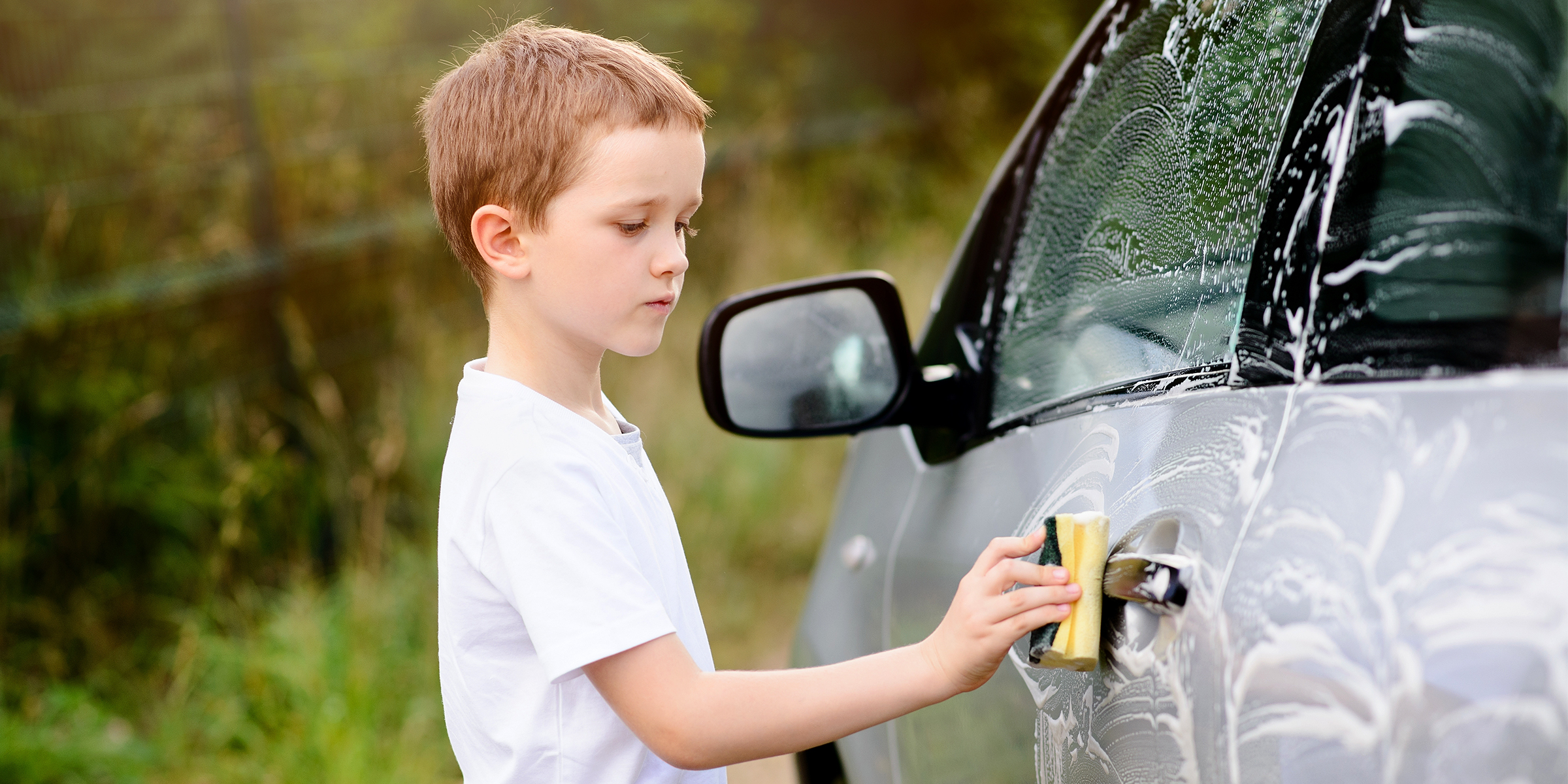 Un garçon nettoie une voiture | Source : Shutterstock