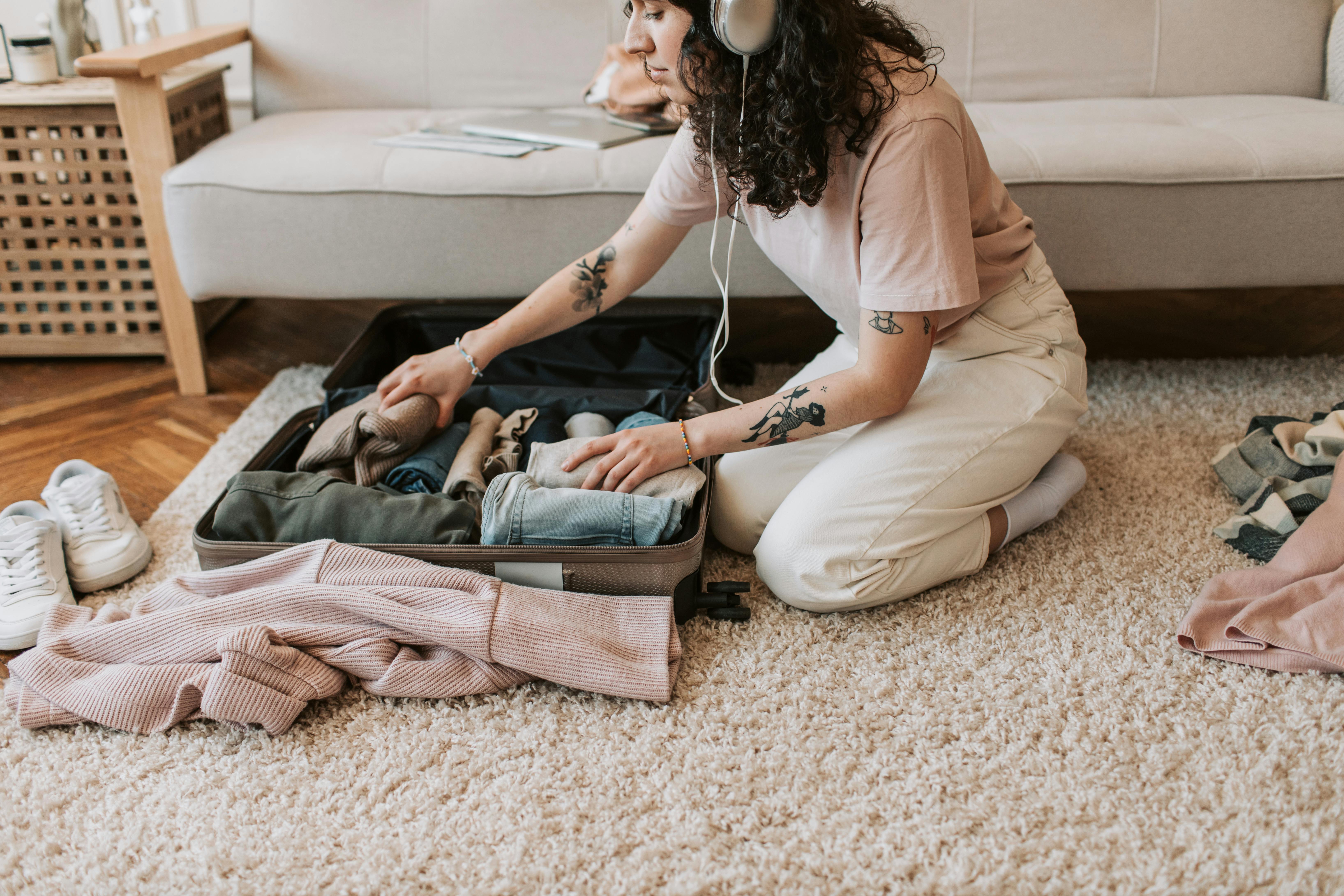 Une femme range ses vêtements tout en portant des écouteurs | Source : Pexels