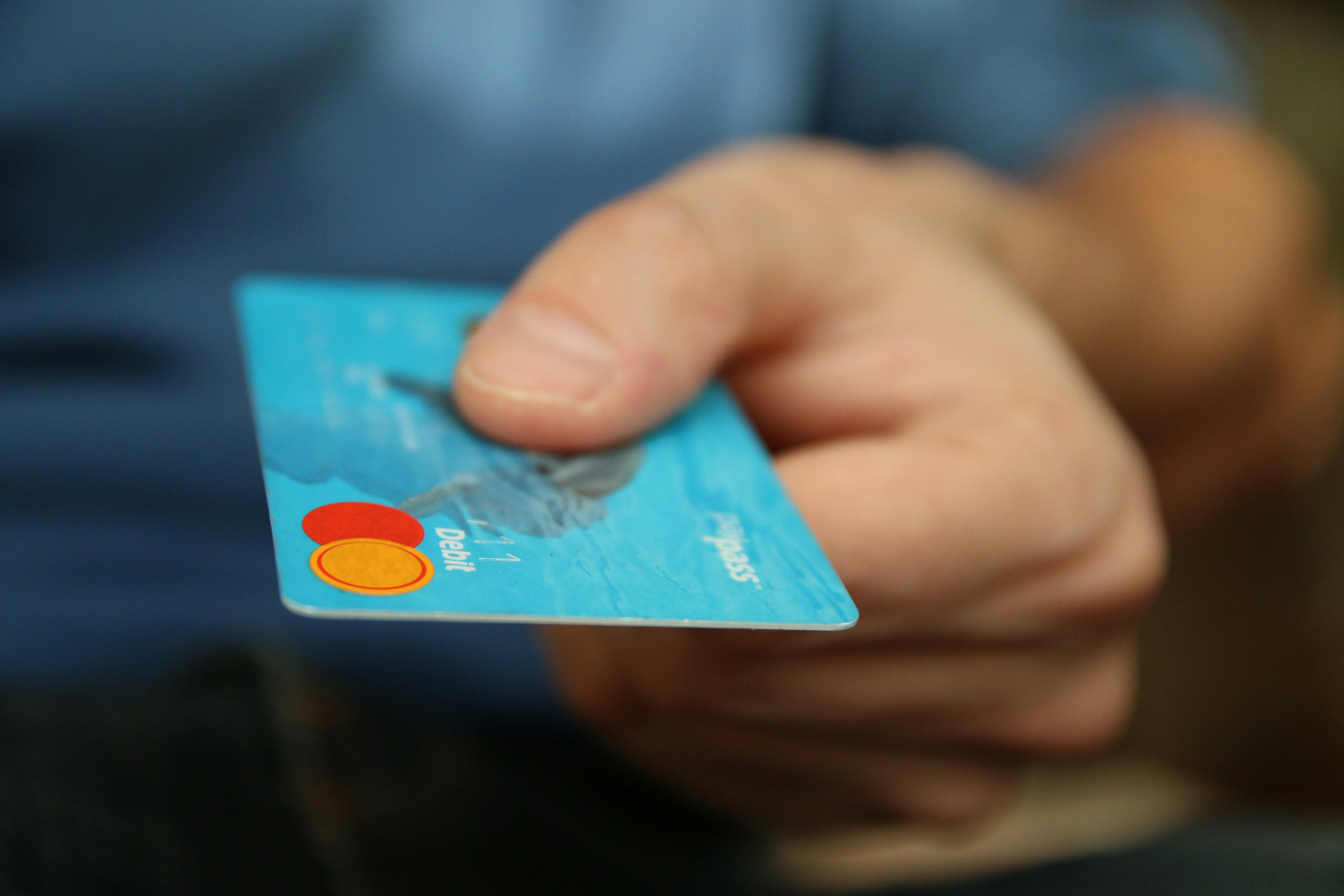 Un homme remettant une carte de débit pour payer quelque chose | Source : Pexels