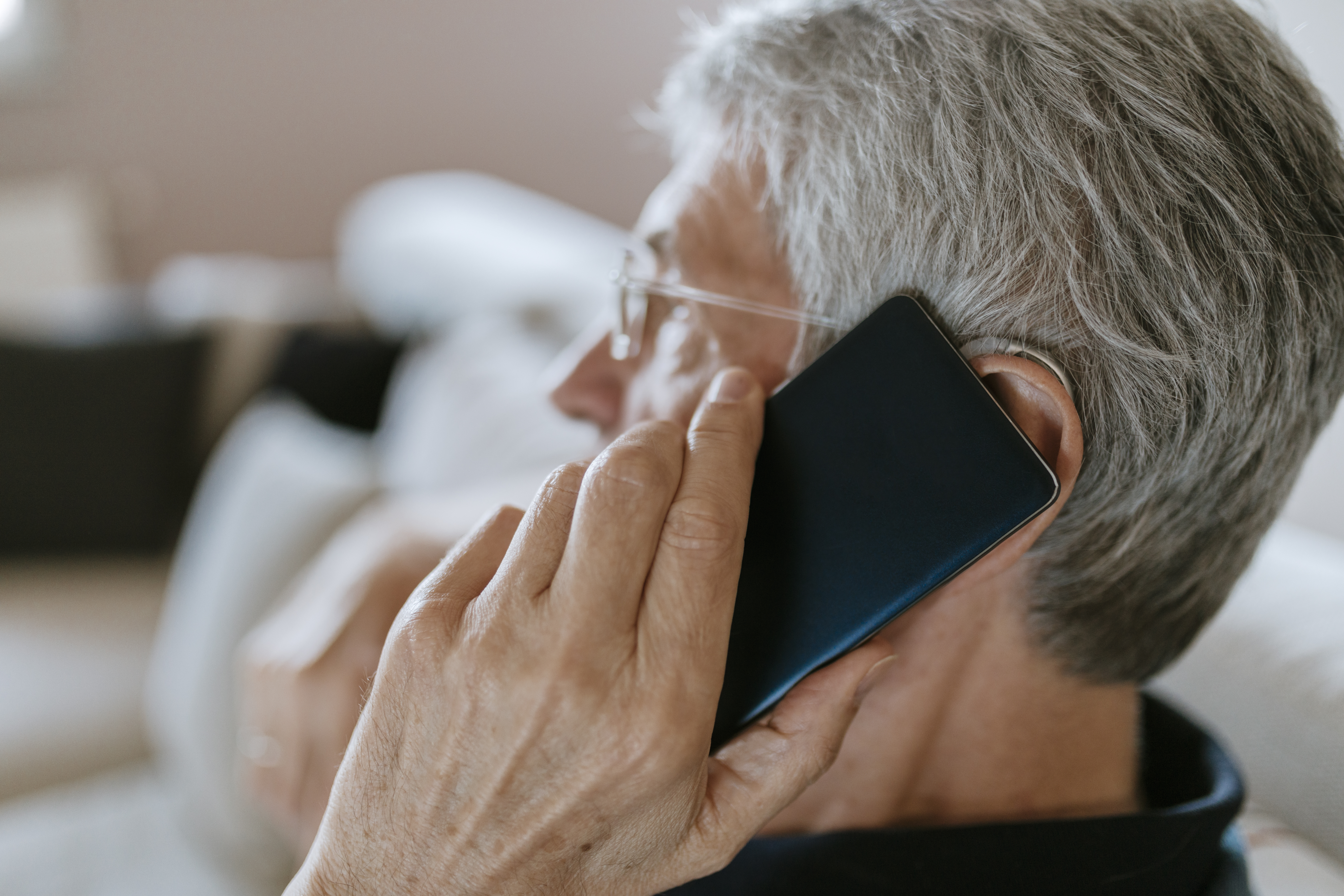 Un homme âgé avec une prothèse auditive parlant au téléphone portable | Source : Getty Images