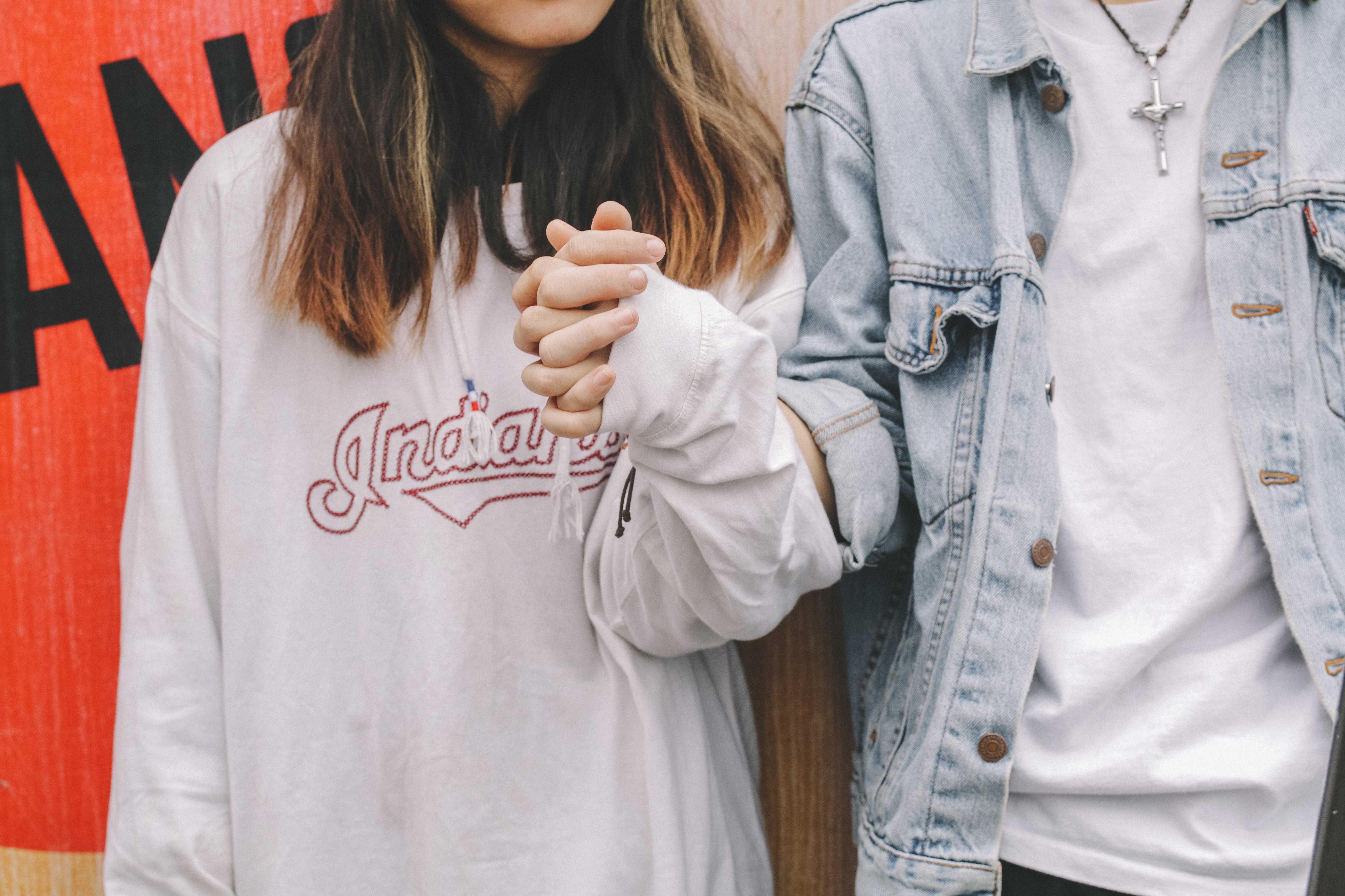 Un jeune couple représenté à partir du cou, se tenant par la main | Source : Pexels