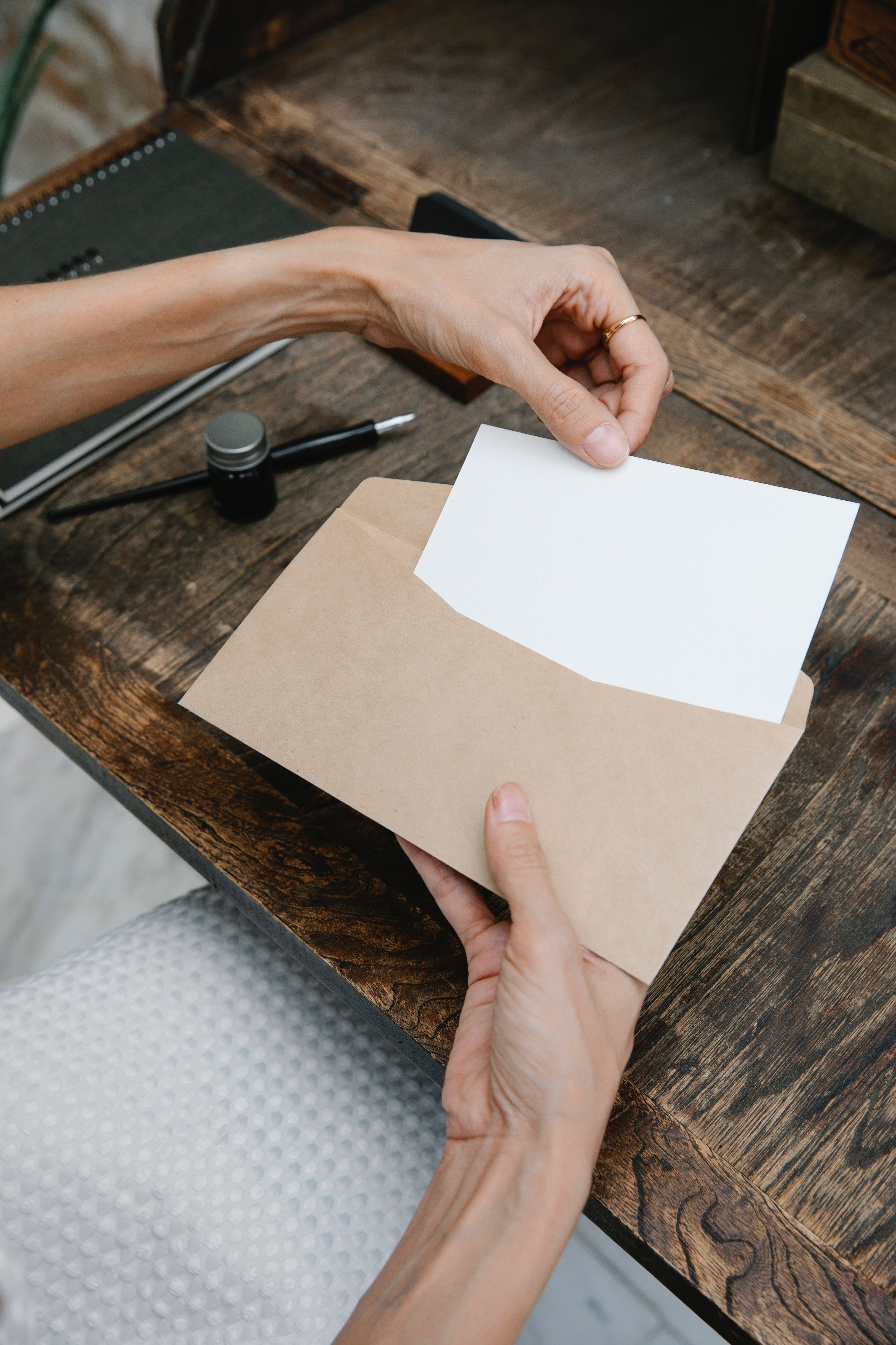 Une femme plaçant une feuille blanche dans une enveloppe | Source : Pexels