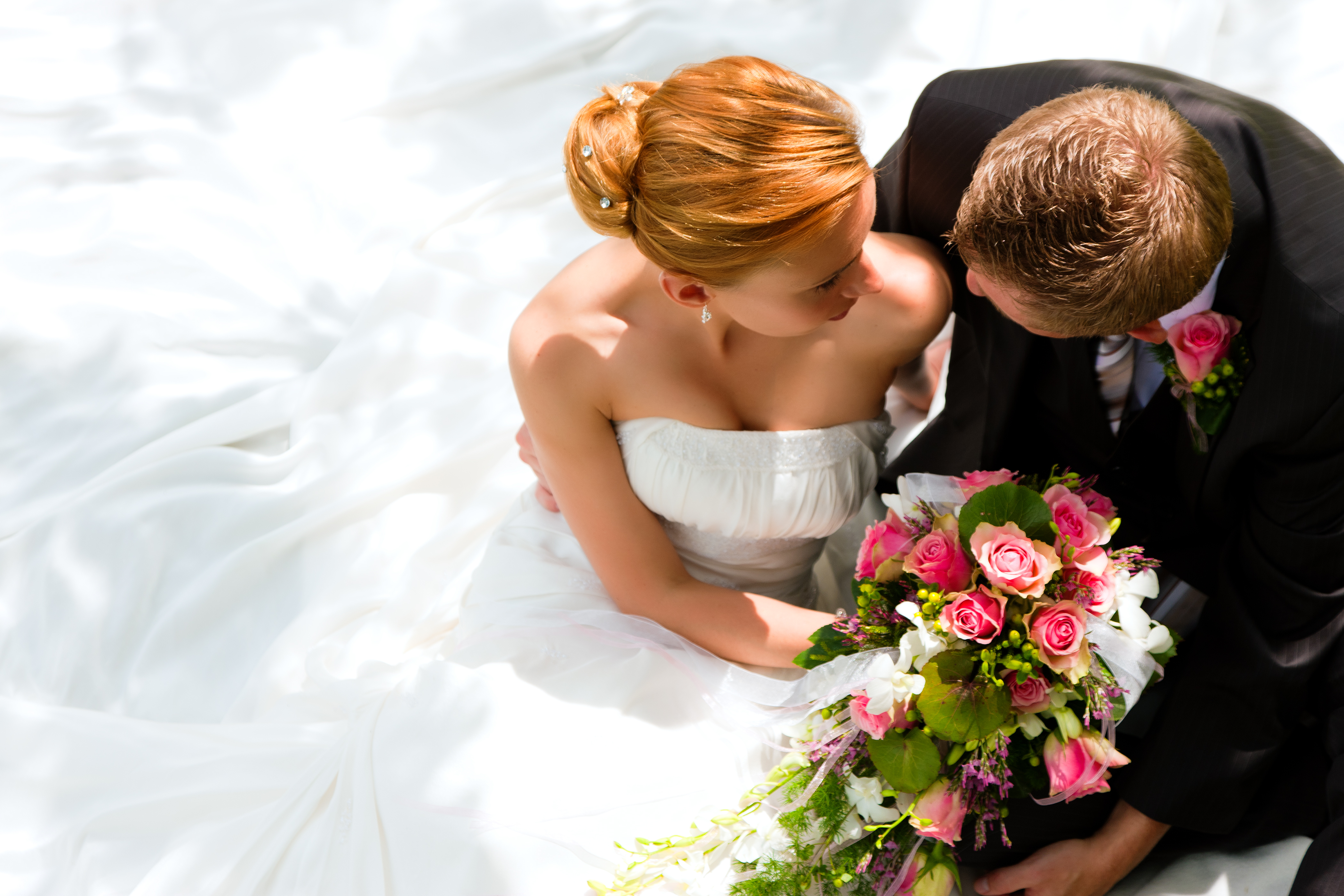 Un marié tenant un bouquet de fleurs est photographié assis à côté de sa fiancée | Source : Shutterstock