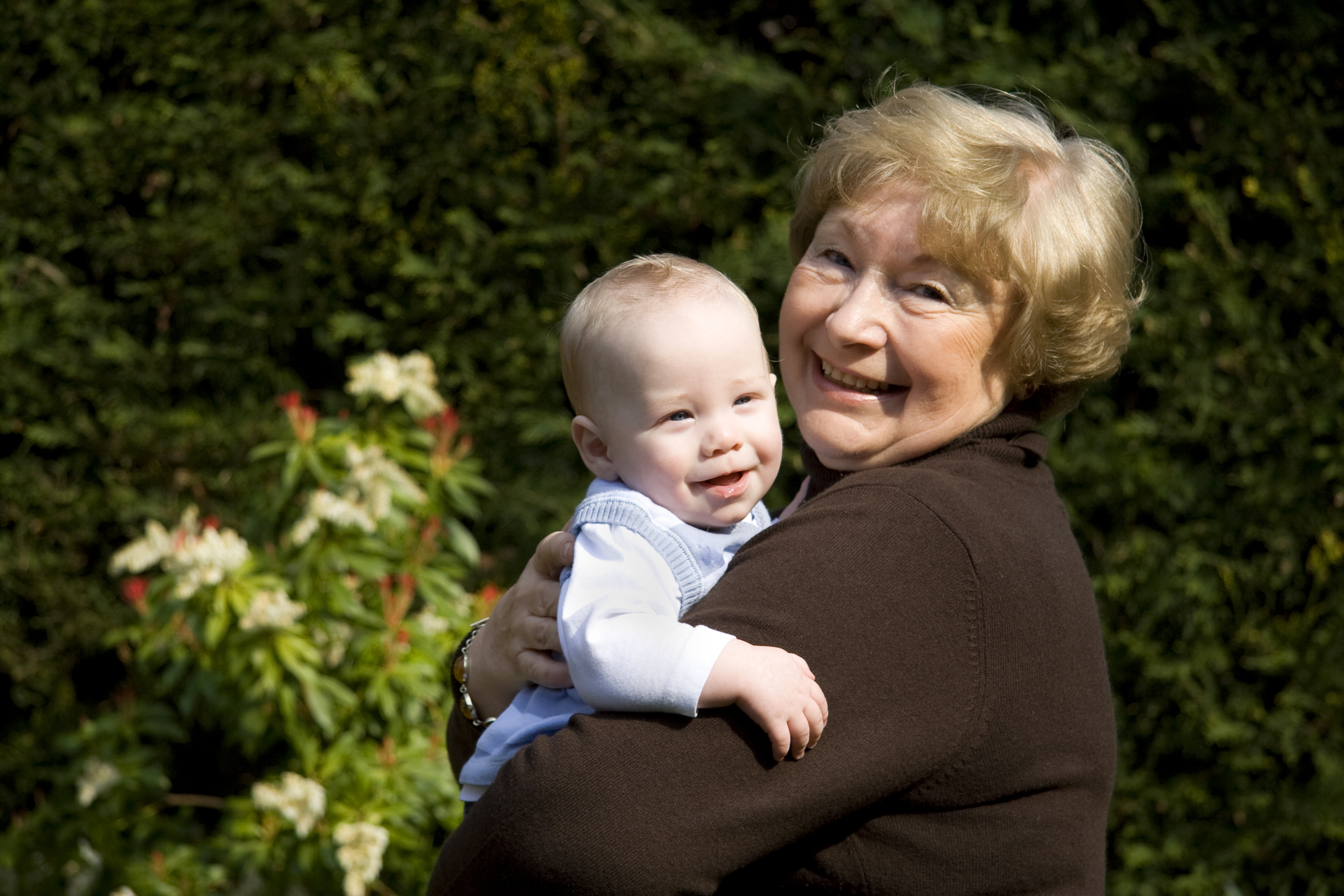 Une femme plus âgée sourit tout en blottissant un bébé heureux | Source : Shutterstock