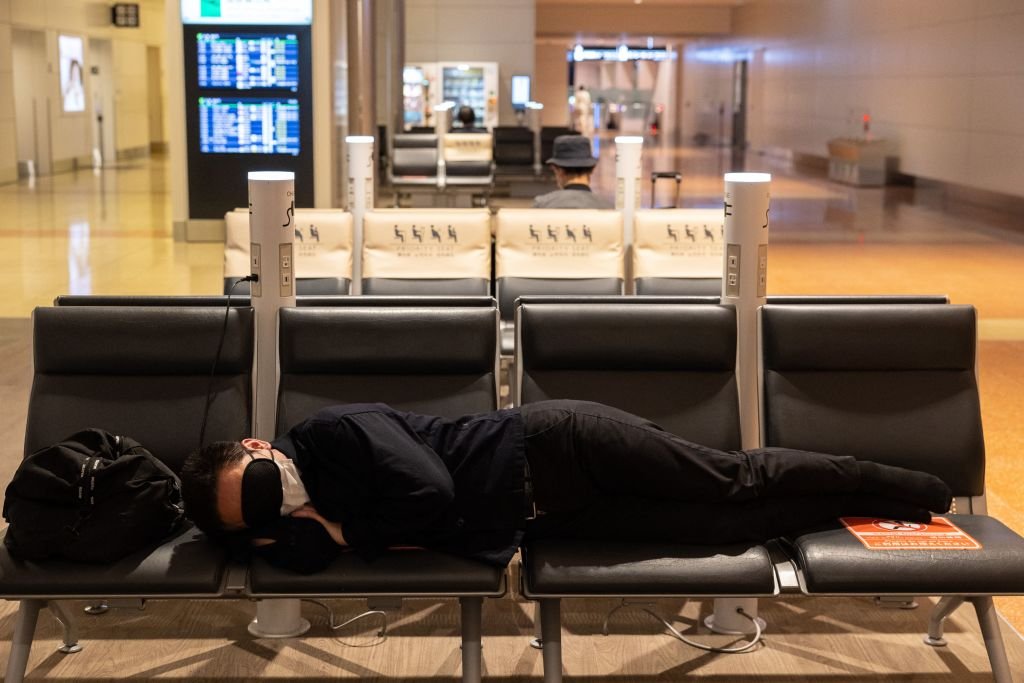 Un homme dort dans un terminal de l'aéroport de Haneda, à Tokyo, le 30 avril 2021. | Photo : Getty Images