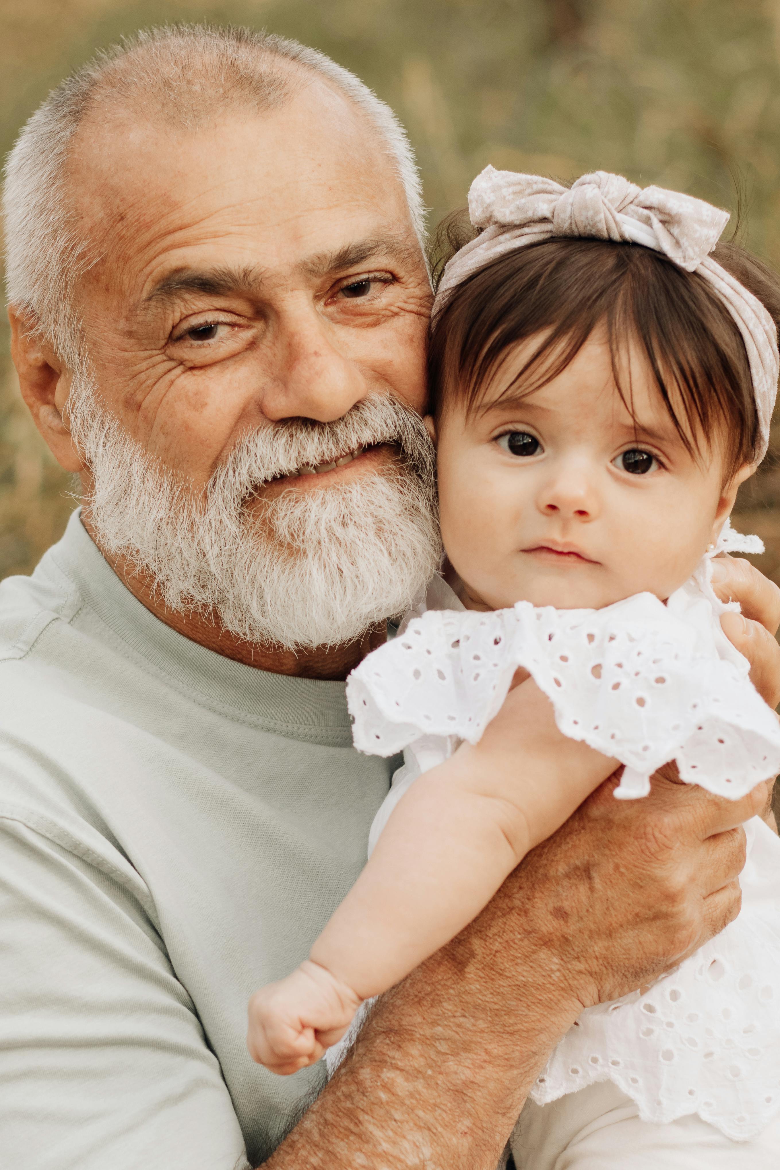 Un homme plus âgé tenant une fillette dans ses bras | Source : Pexels