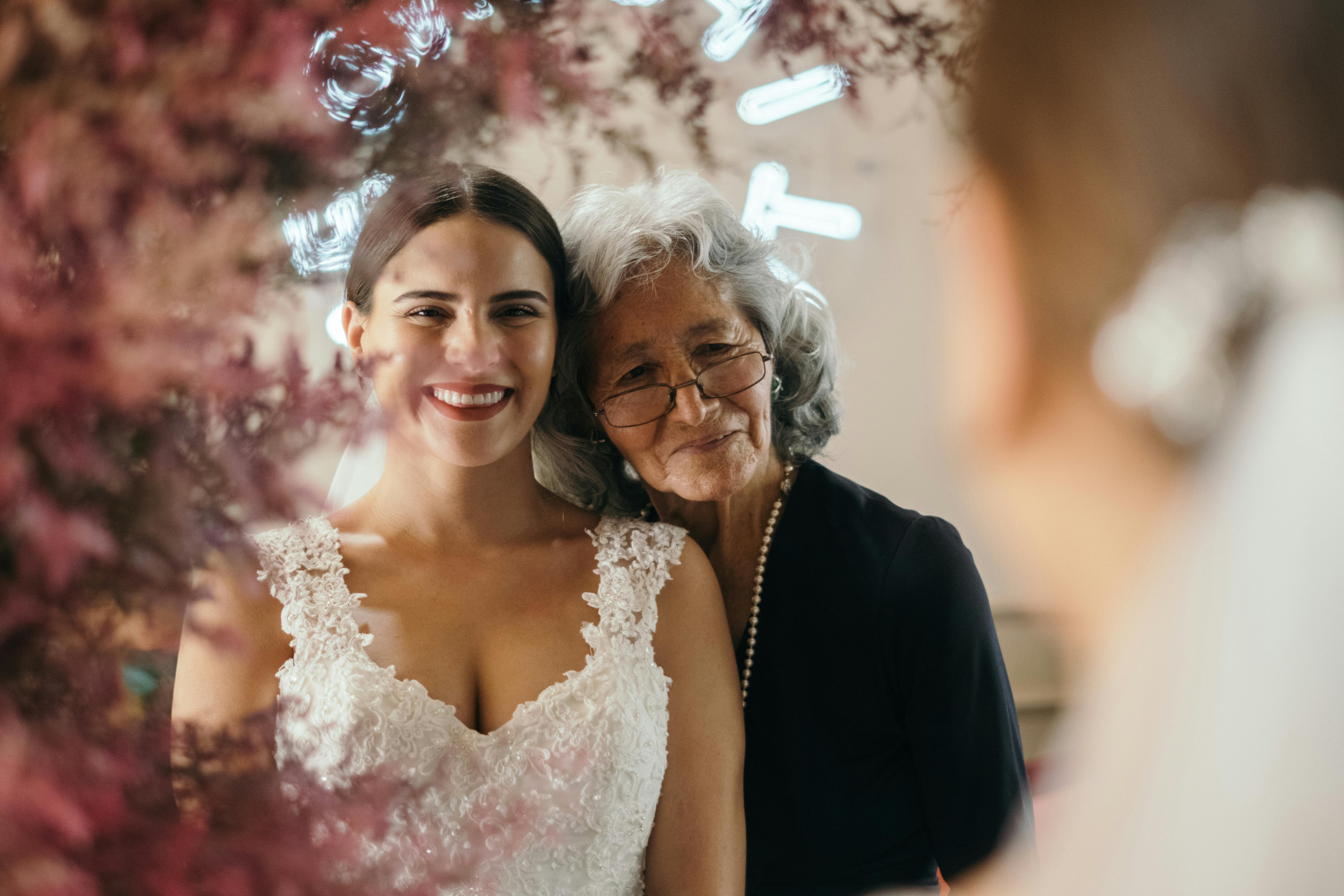 Une mariée et une femme plus âgée inspectent l'ajustement d'une robe de mariée | Source : Pexels