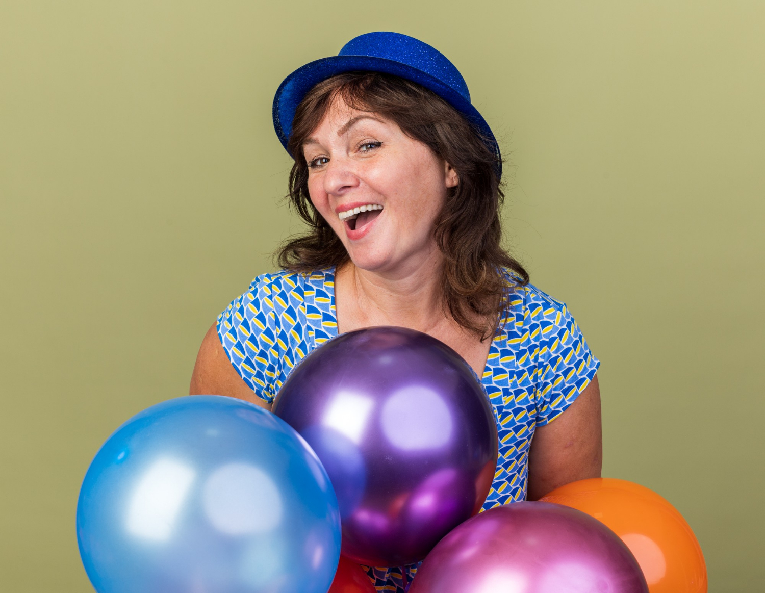 Une femme joyeuse d'âge moyen tenant des ballons colorés | Source : Freepik