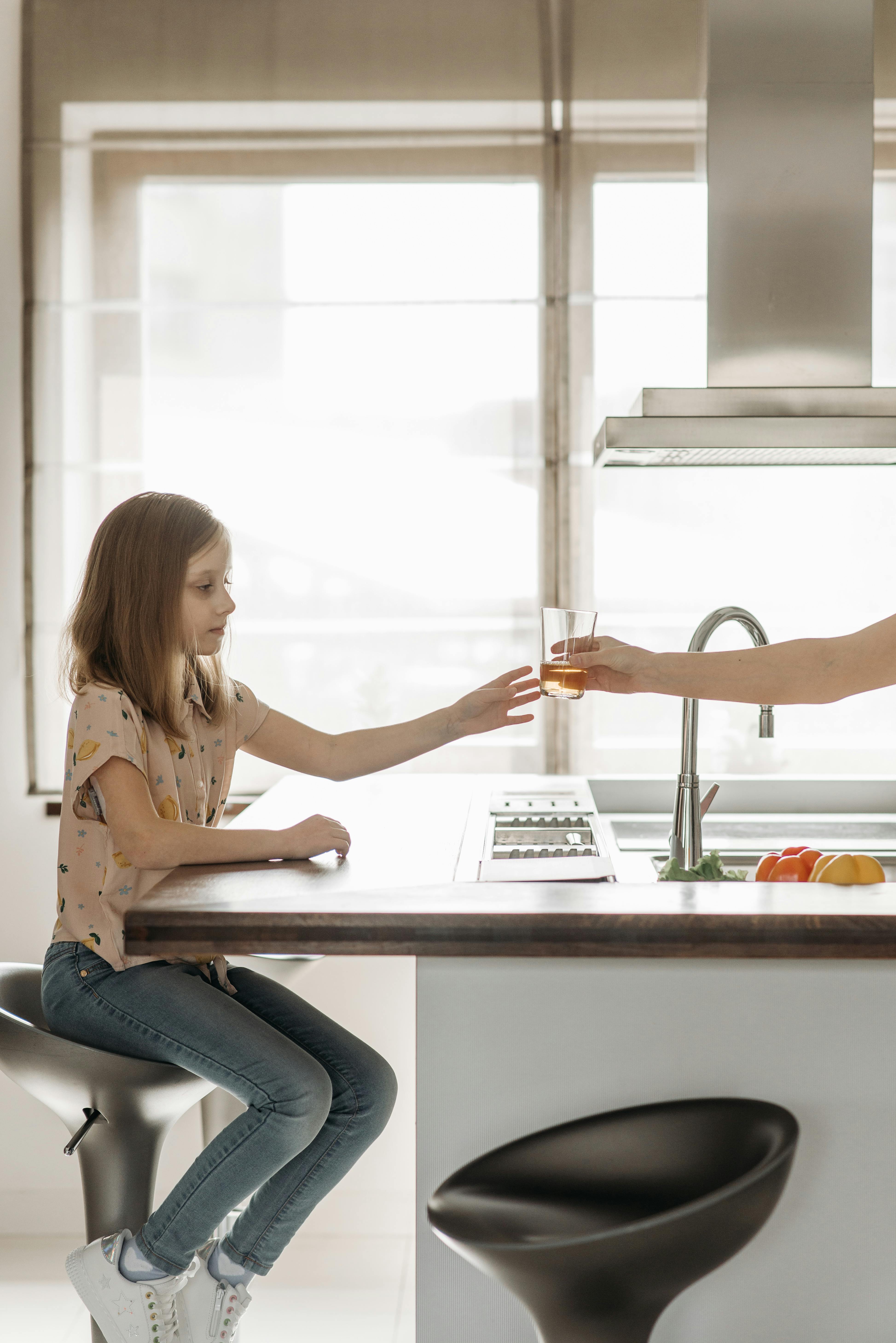 Une femme donne un jus de fruit à une enfant | Source : Pexels