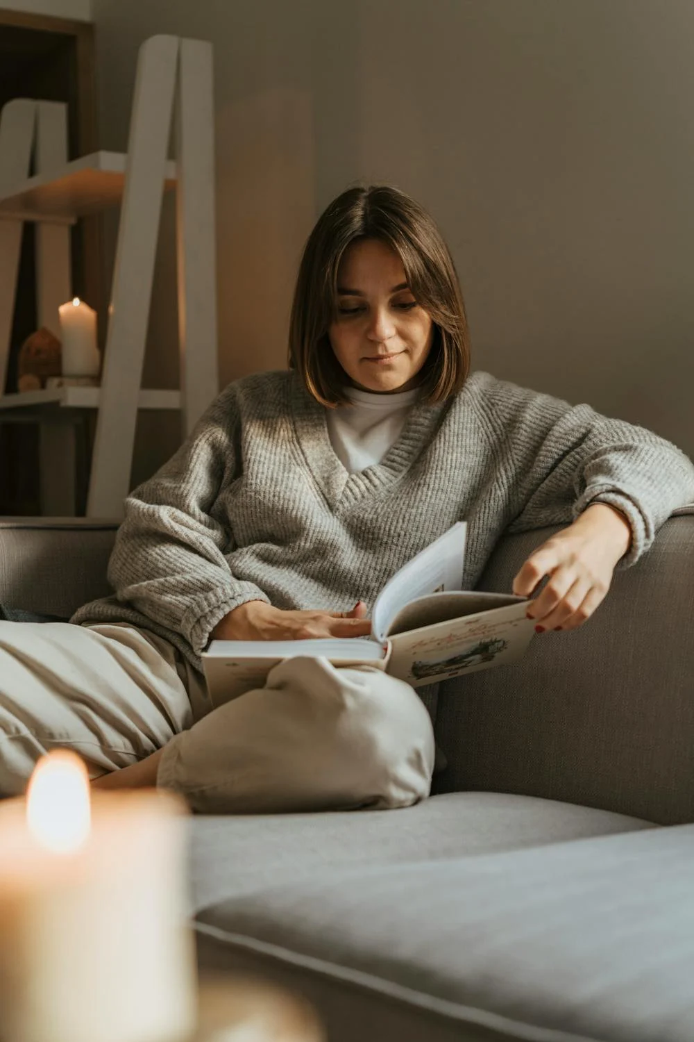 A woman reading a book on a sofa | Source: Pexels