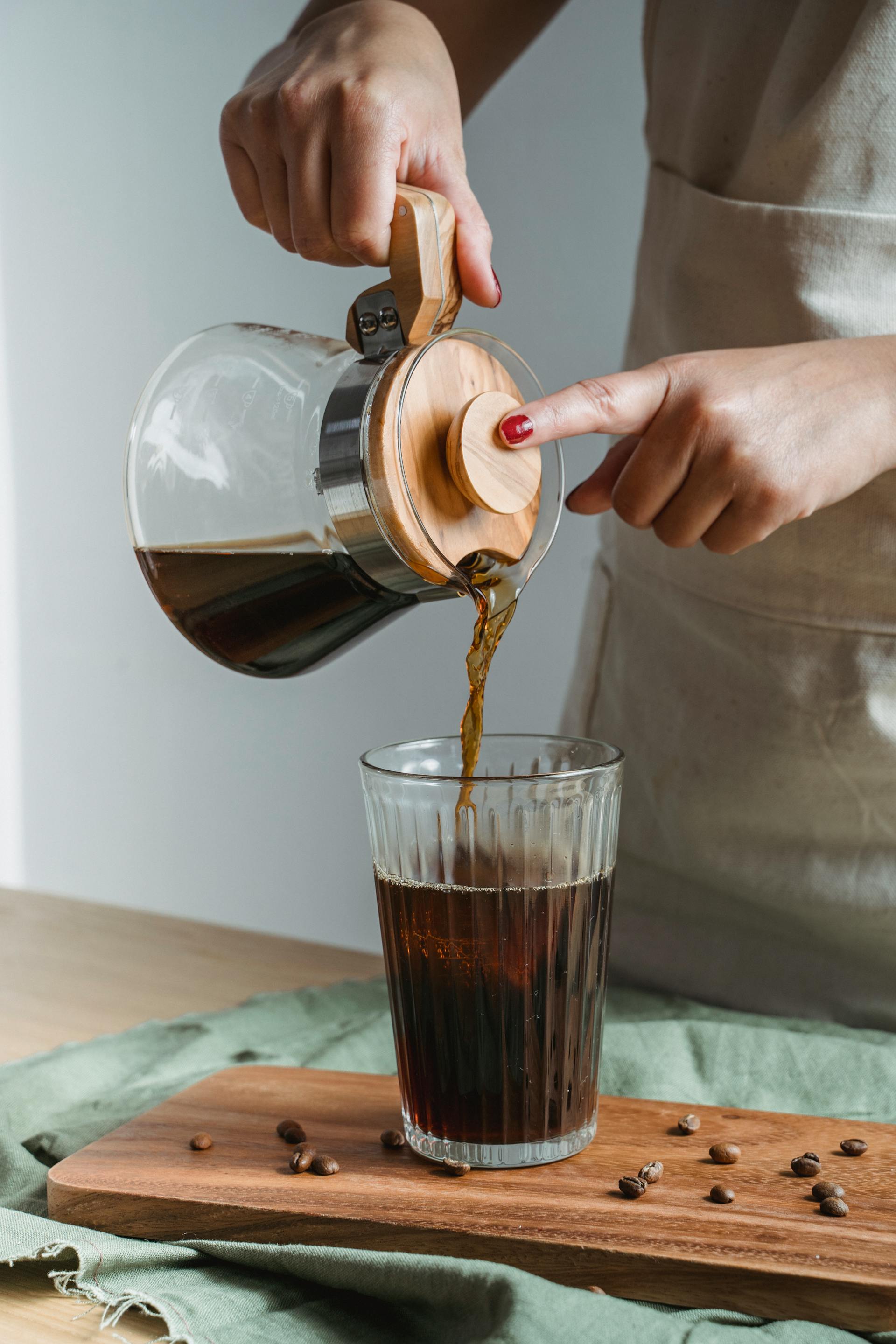 Une femme versant du café noir dans un verre | Source : Pexels