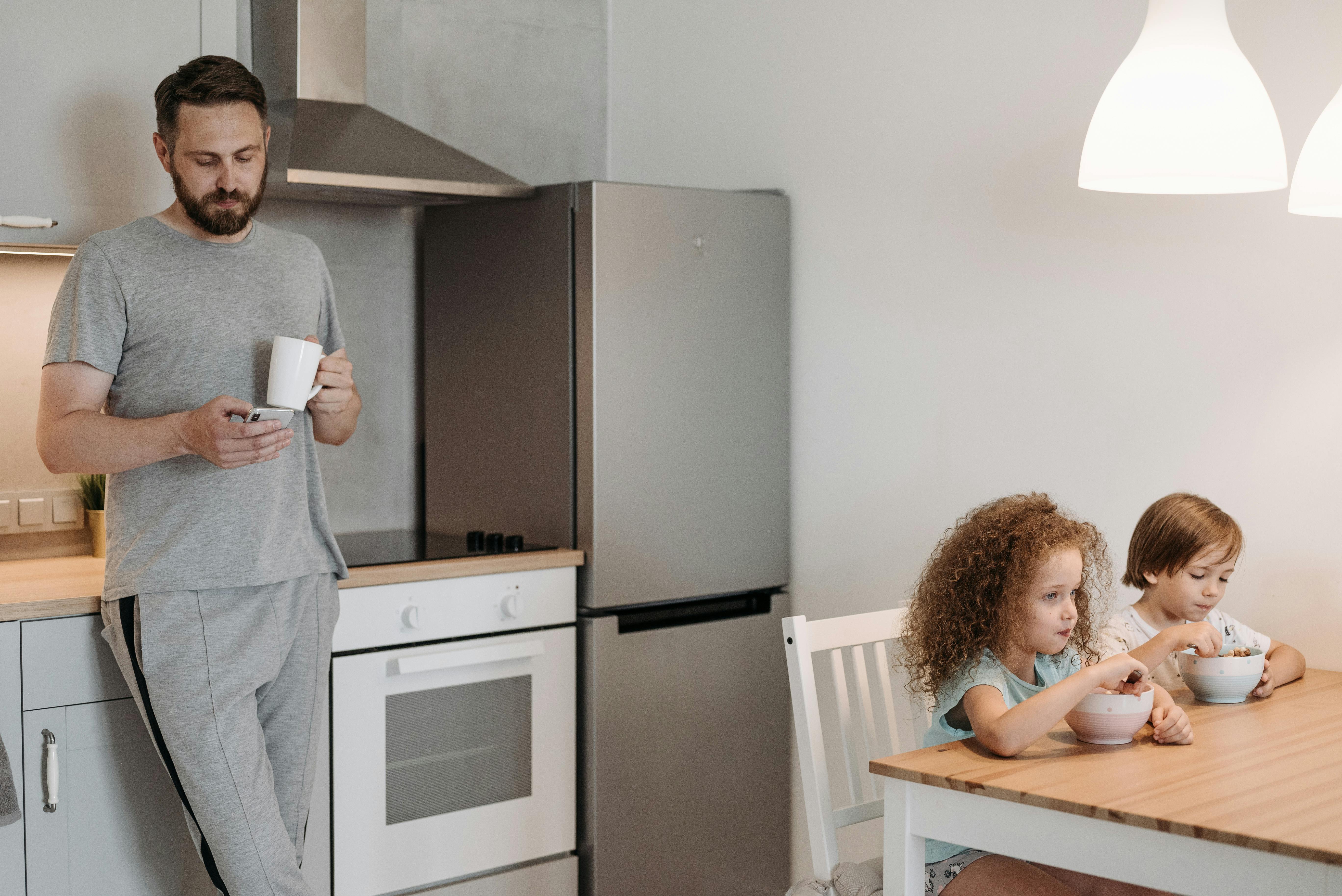 Un homme utilisant son téléphone pendant que ses enfants mangent | Source : Pexels
