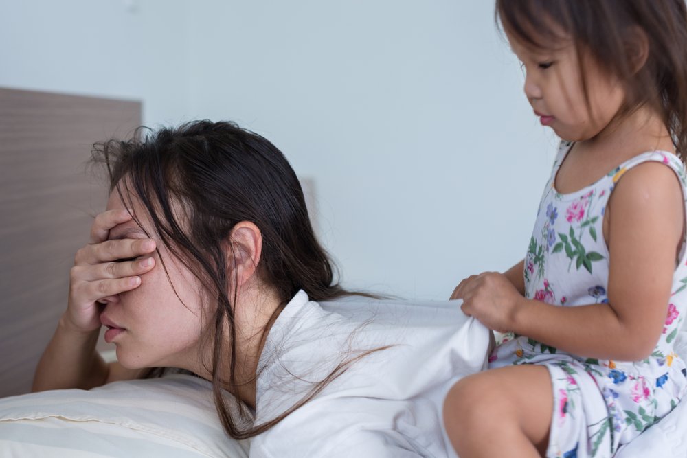 Une mère épuisée et accablée avec son enfant à la maison. | Shutterstock