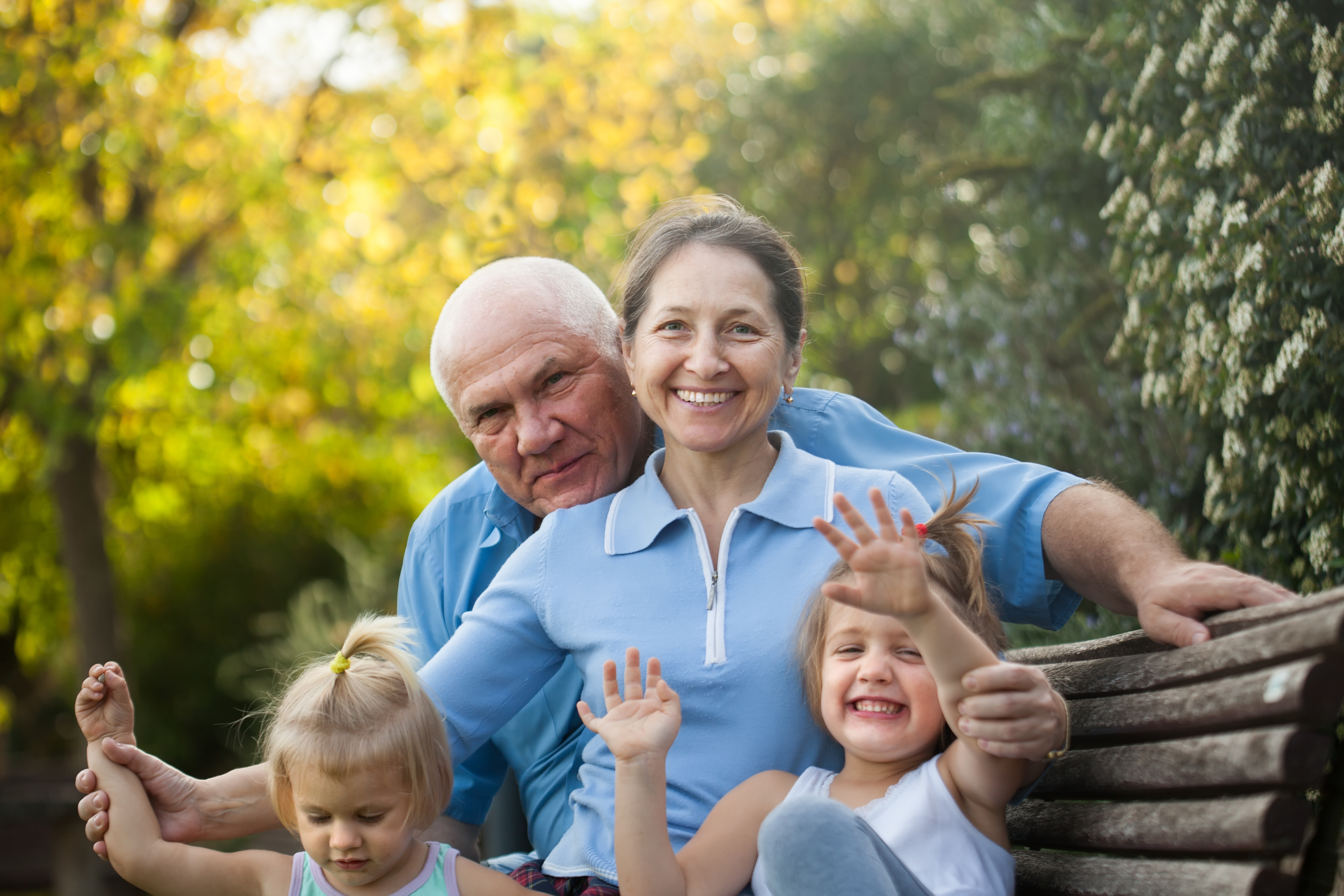 Couple de seniors assis avec leurs petits-enfants dans un parc | Source : Shutterstock