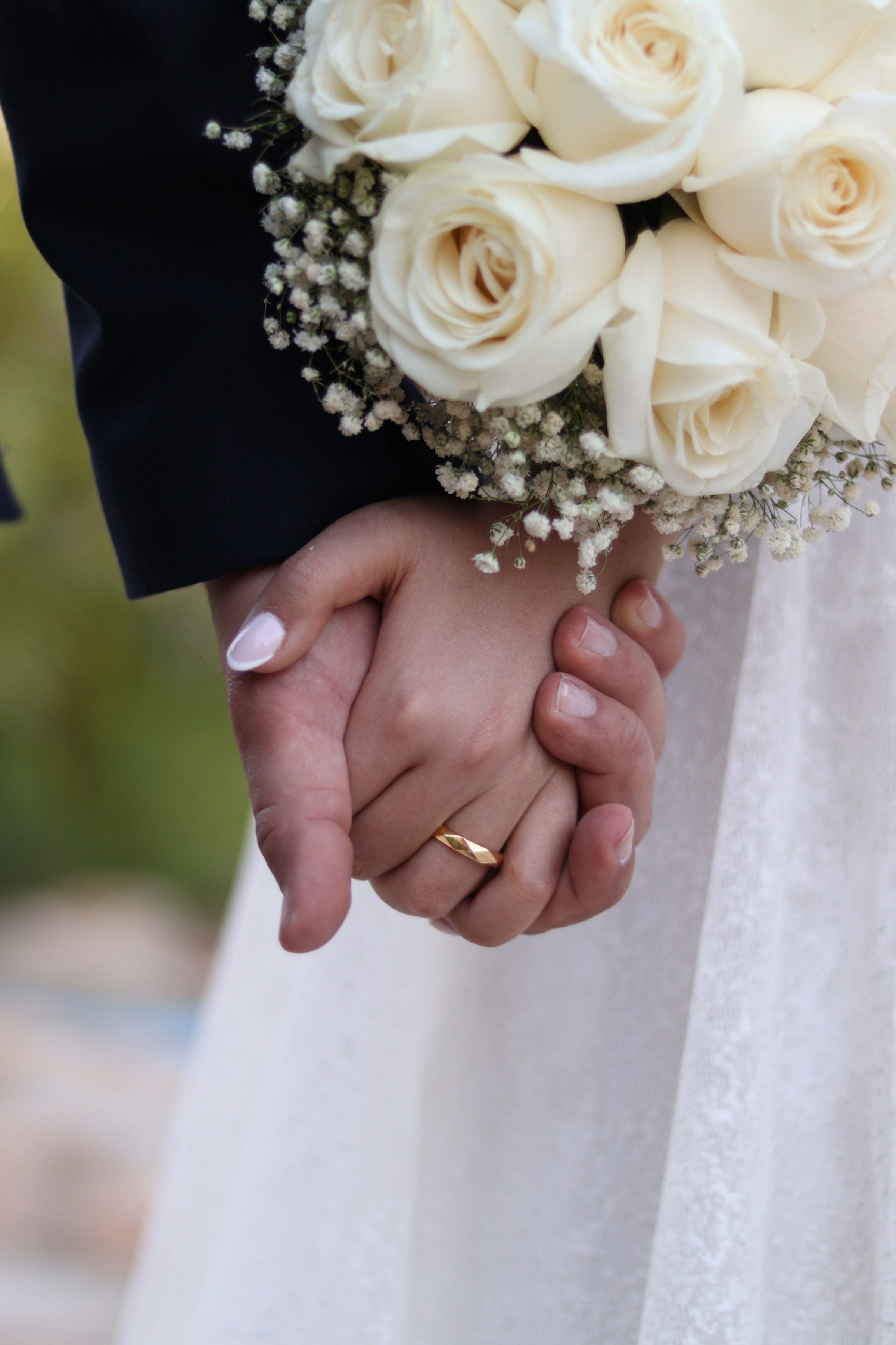 Gros plan d'une mariée et d'un marié se tenant par la main | Source : Unsplash