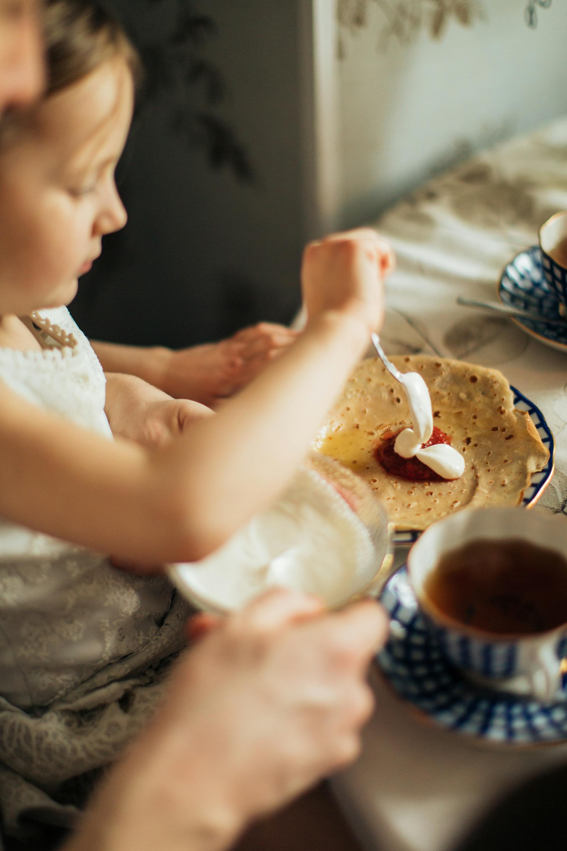 Une jeune fille étalant de la confiture et de la crème sur une crêpe | Source : Pexels