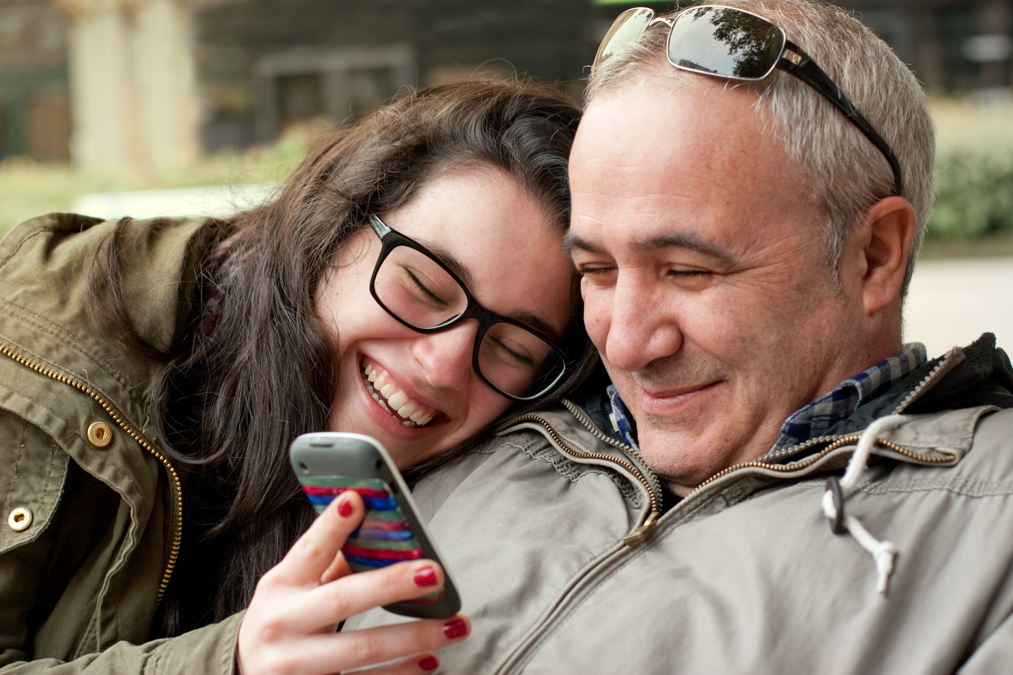 Une femme riant en montrant son téléphone portable à un homme | Source : Shutterstock