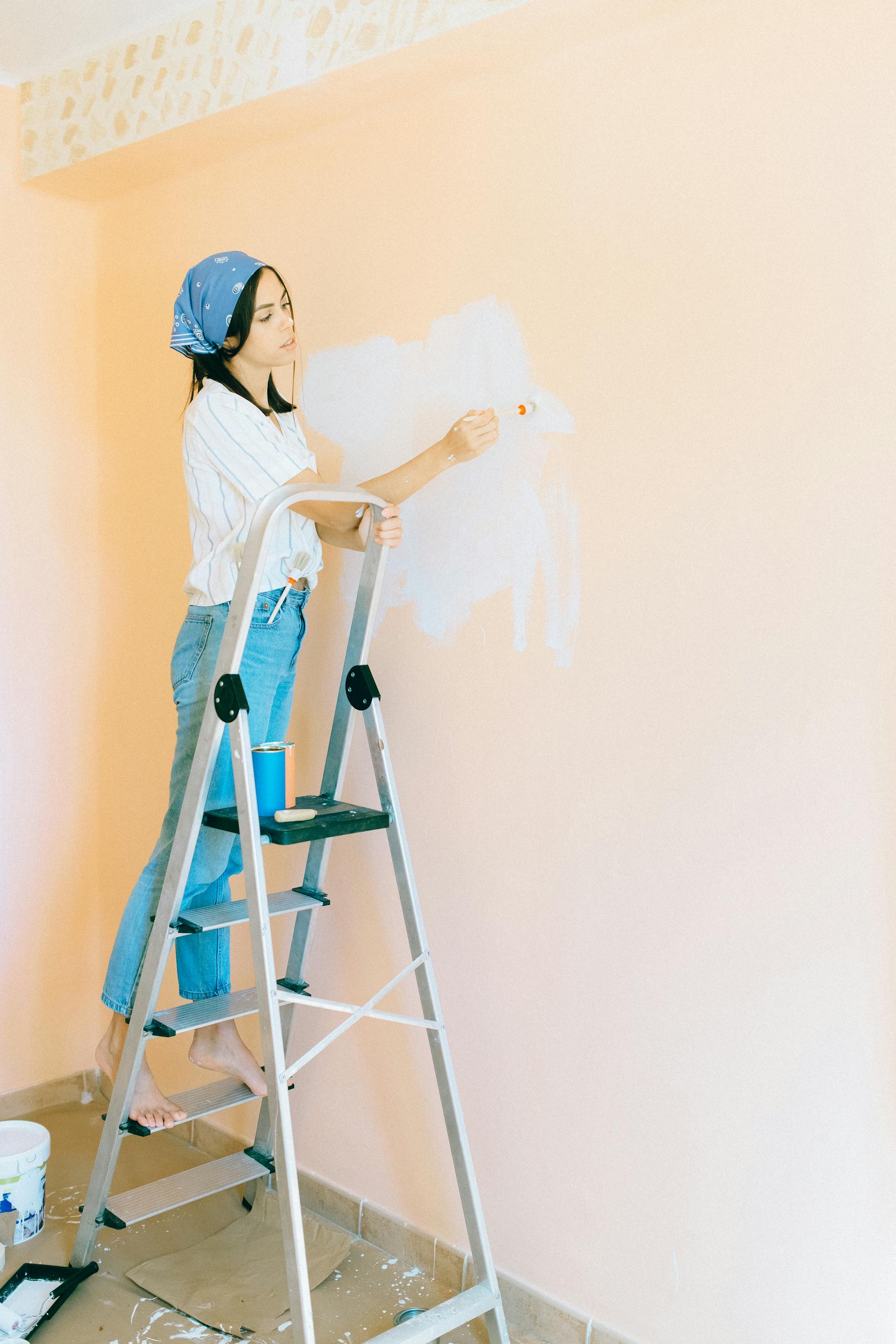 Une femme debout sur un escabeau et peignant un mur | Source : Pexels