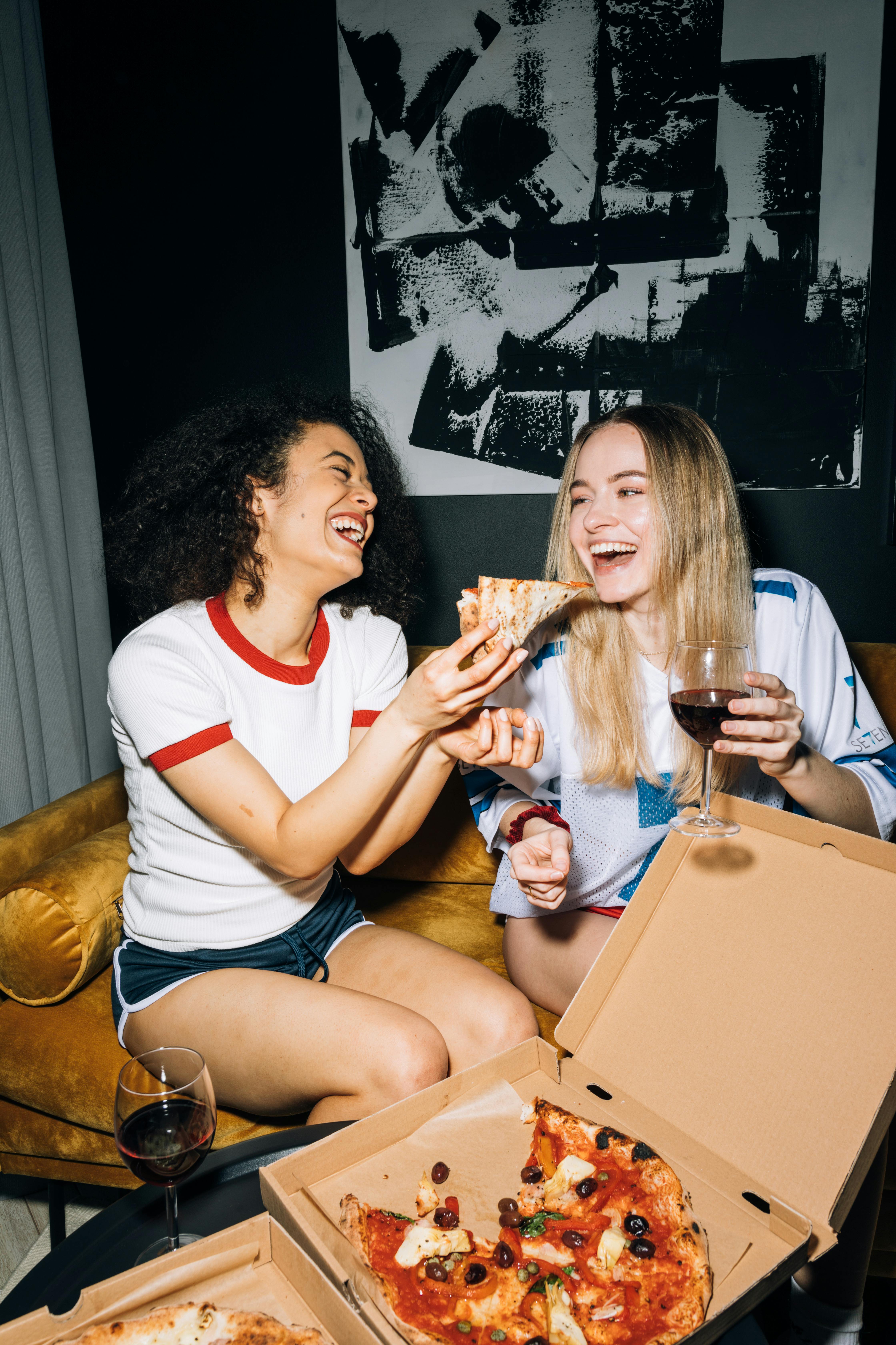 Des femmes dégustent une pizza et du vin | Source : Pexels