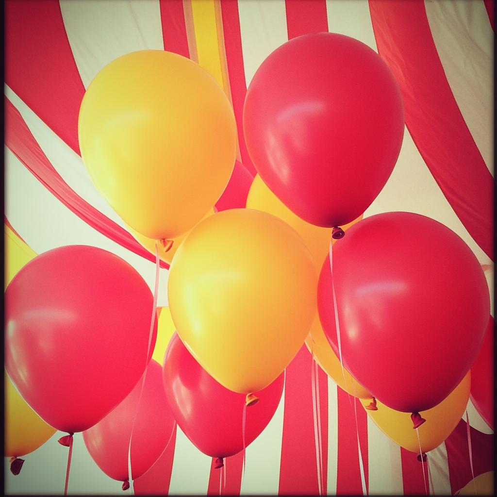 Ballons rouges et jaunes lors d'une fête prénatale sur le thème du cirque | Source : Midjourney